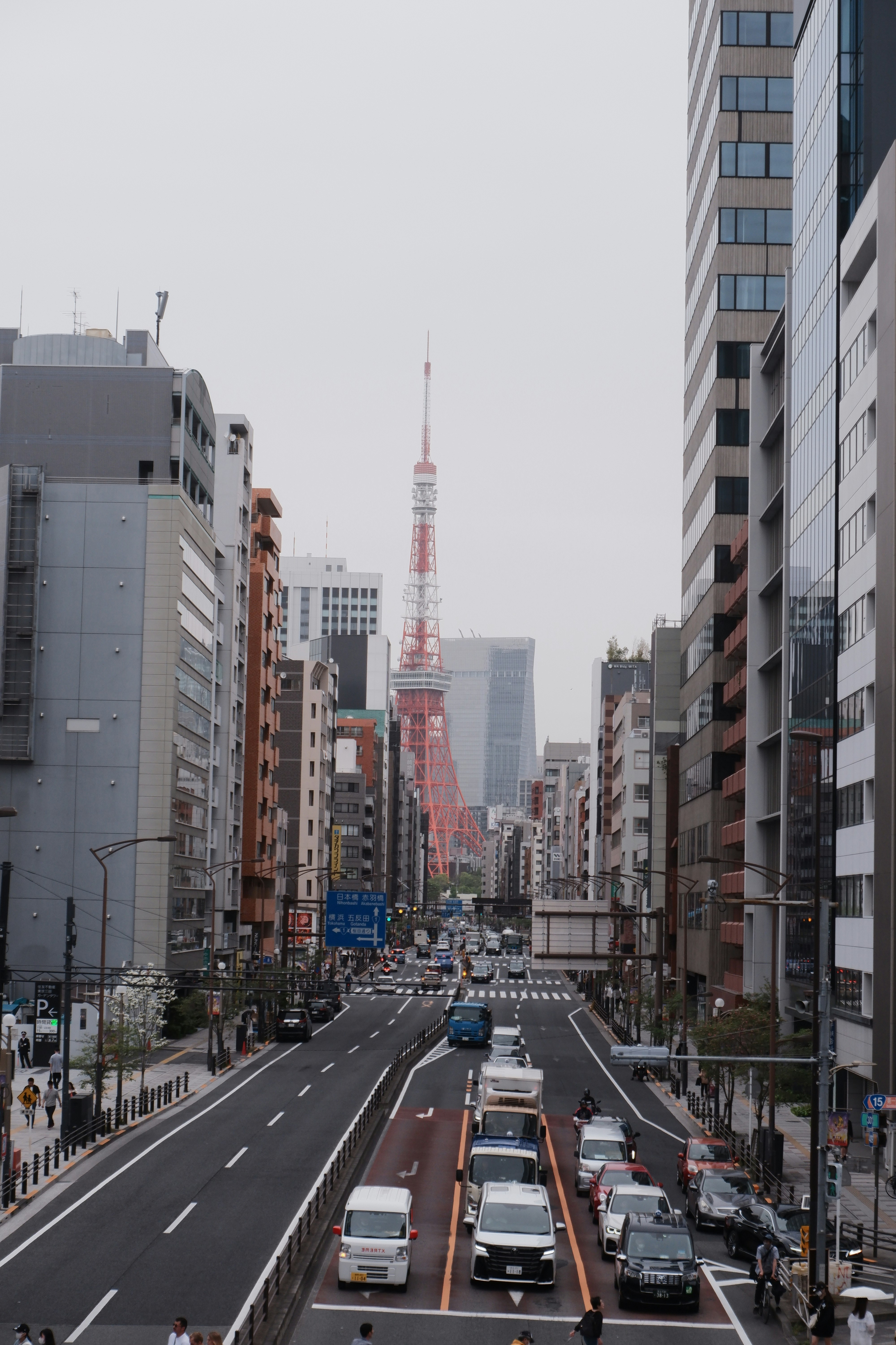 高層ビルに挟まれた東京タワーが見える大通り