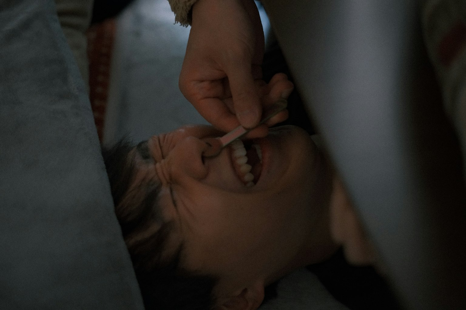 人が寝ている間に他の人が彼の鼻に何かを入れようとしているシーン