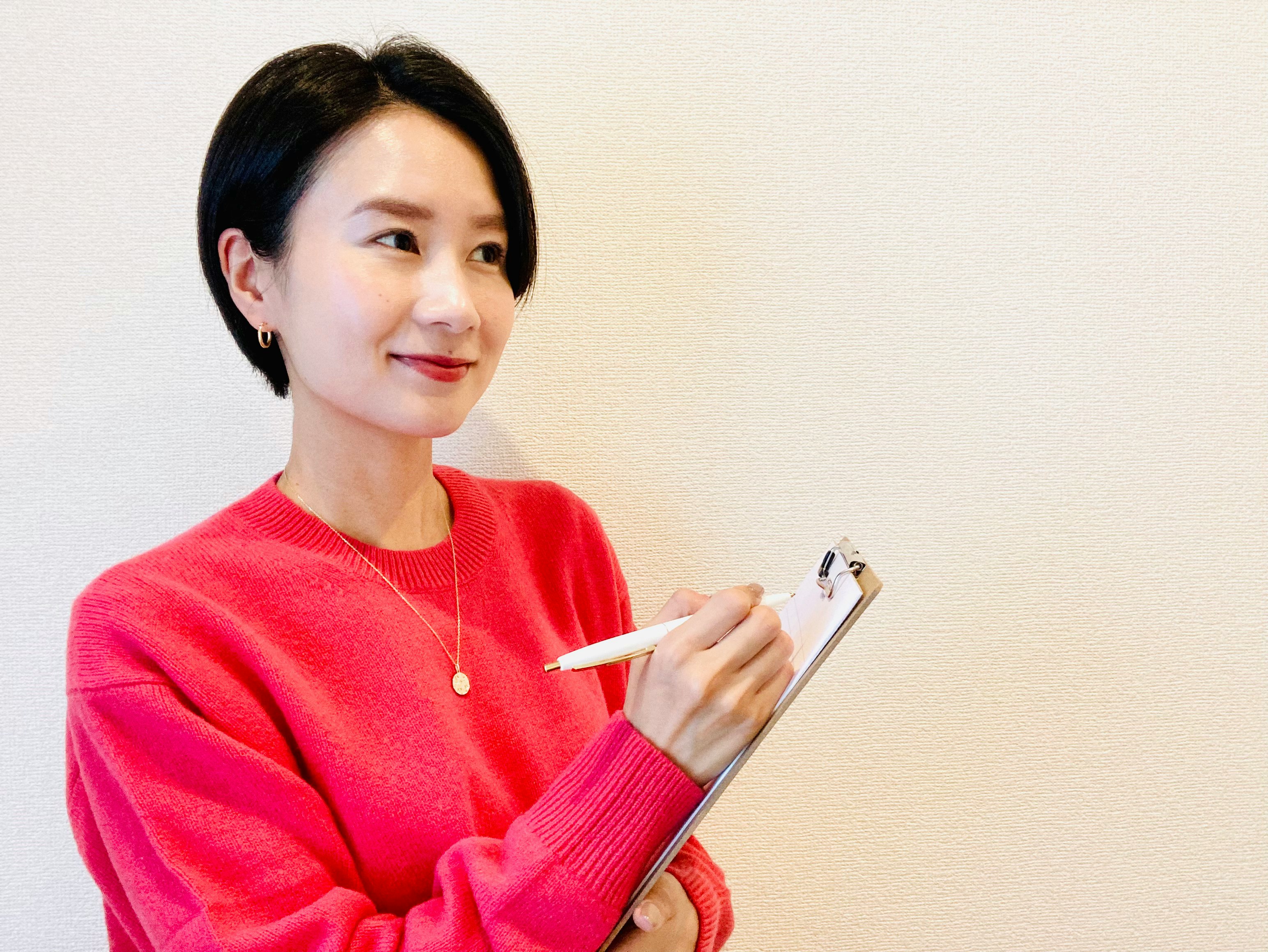 Woman in a red sweater holding a clipboard