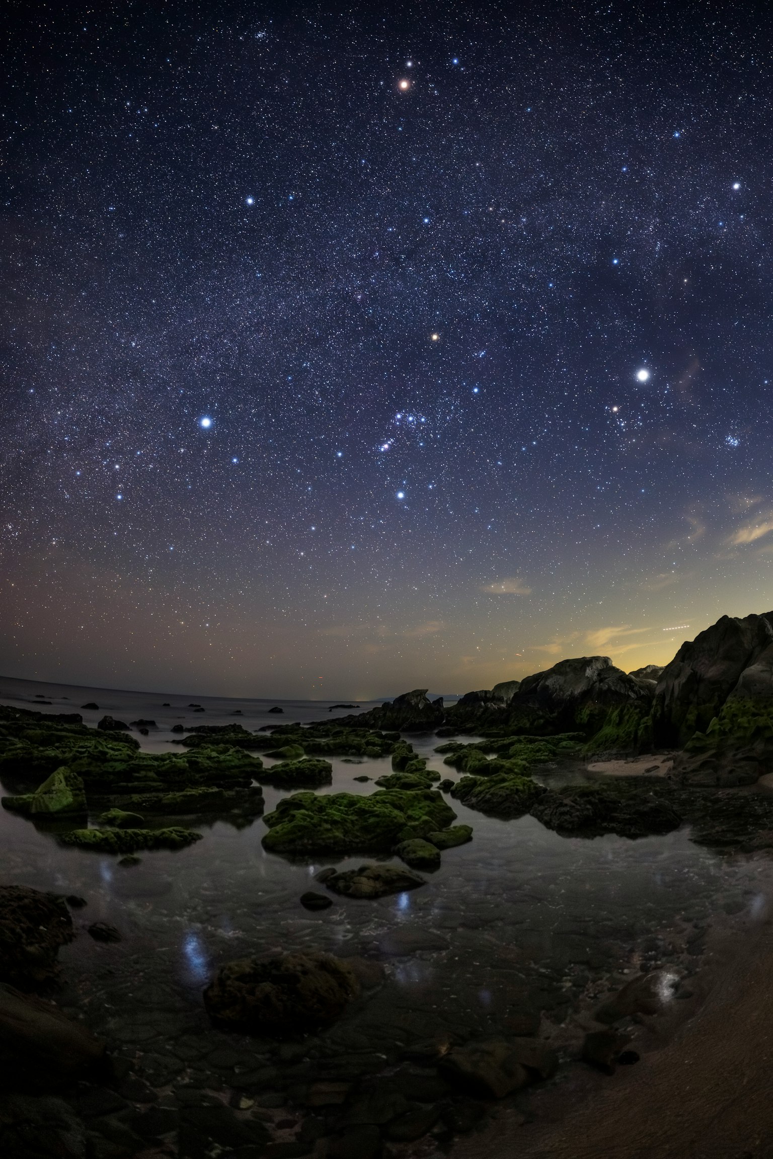 星空映衬下的岩石海岸和水中的倒影