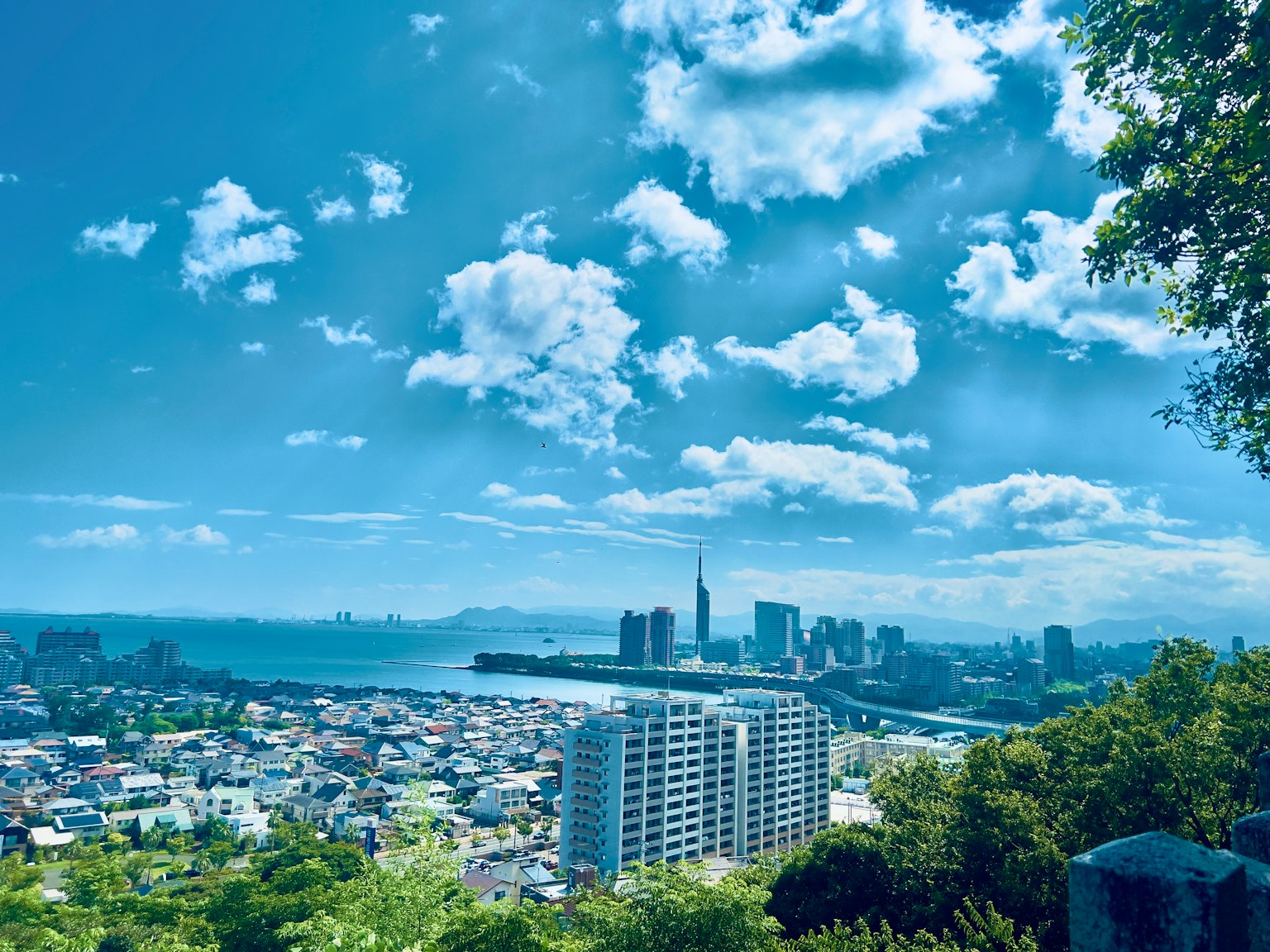 Cityscape with blue sky and white clouds featuring skyscrapers and a river