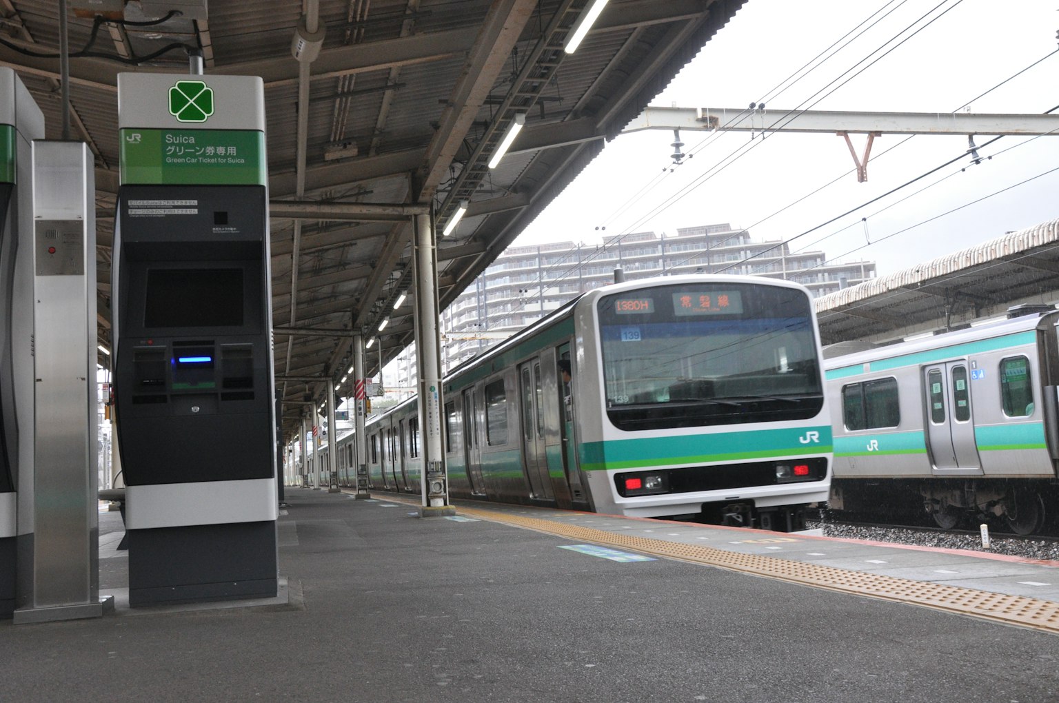 綠色列車停靠在車站月台旁的自動售票機