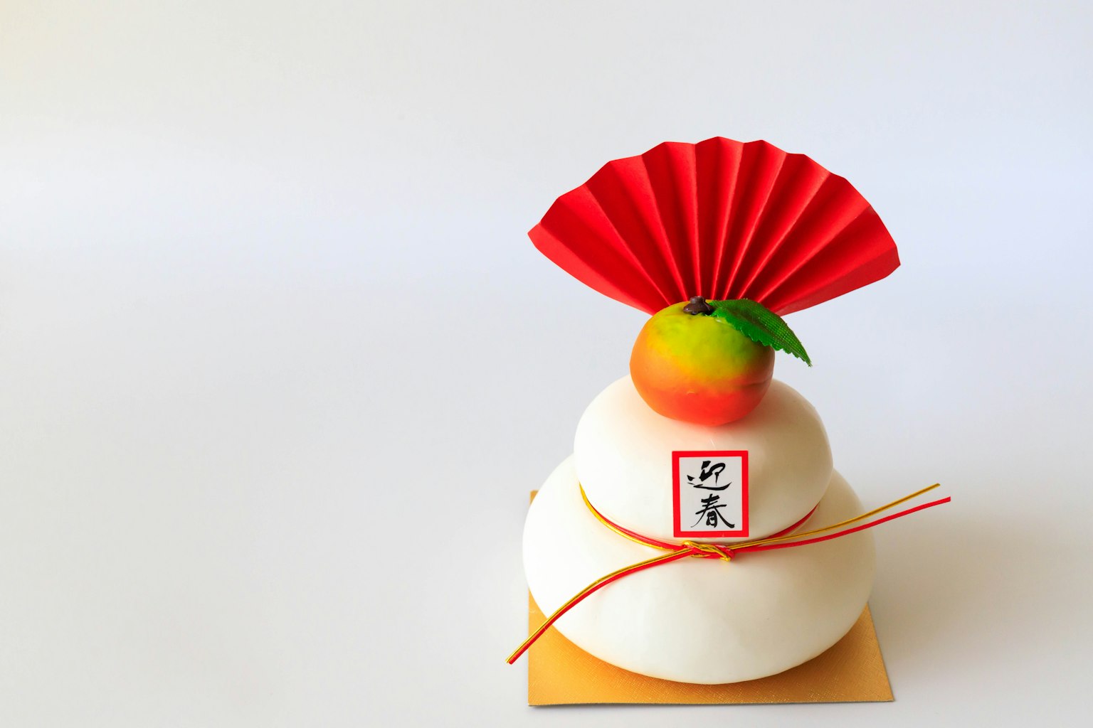 Kagami mochi decorativo con un ventaglio rosso e un mandarino in cima