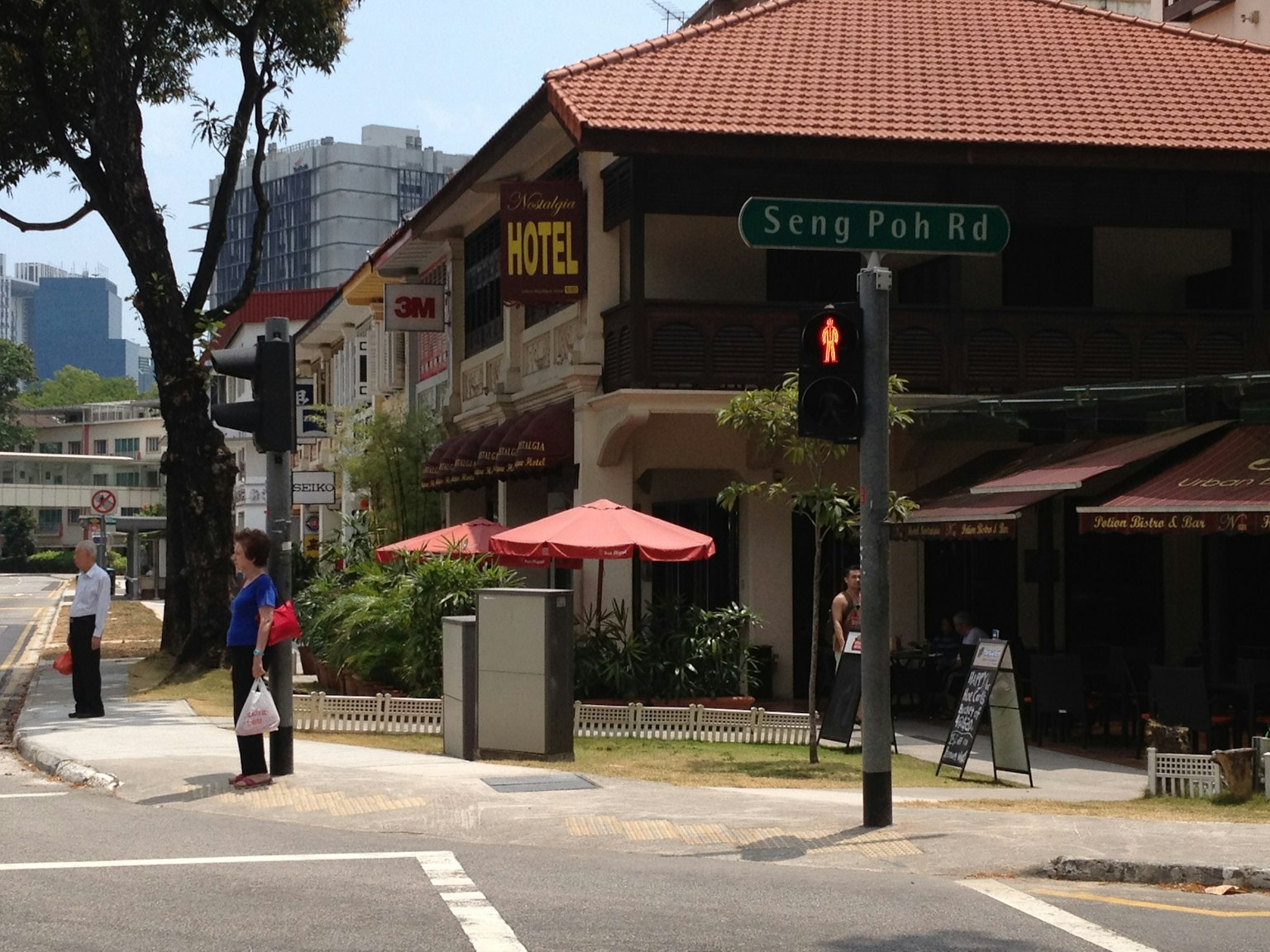 Orang-orang menunggu di sudut jalan dekat kafe dengan payung
