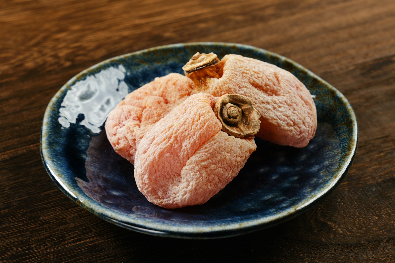 Plum umeboshi merah muda disajikan di piring biru