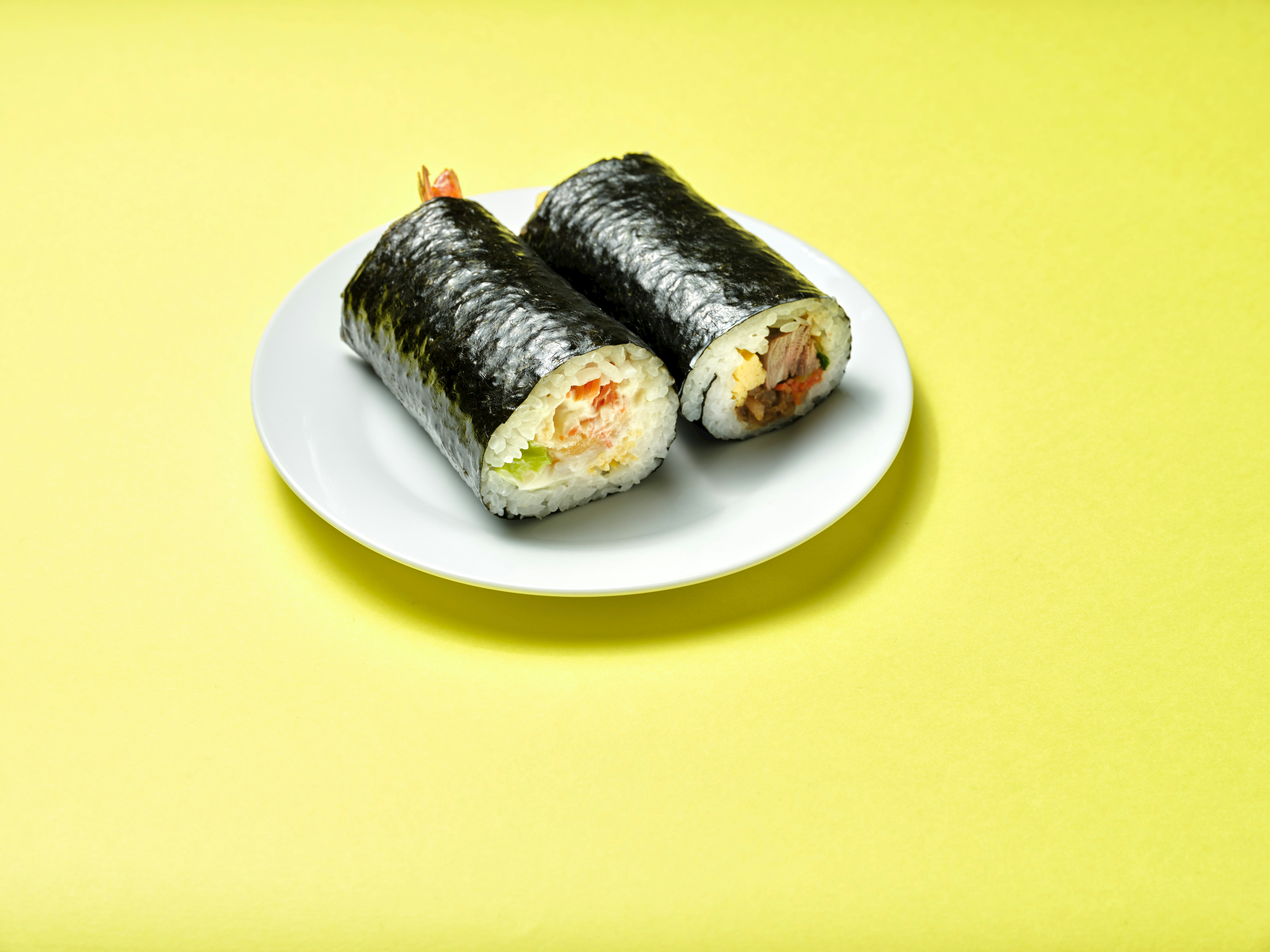 sushi maki rong biển nori trên đĩa trắng nền vàng