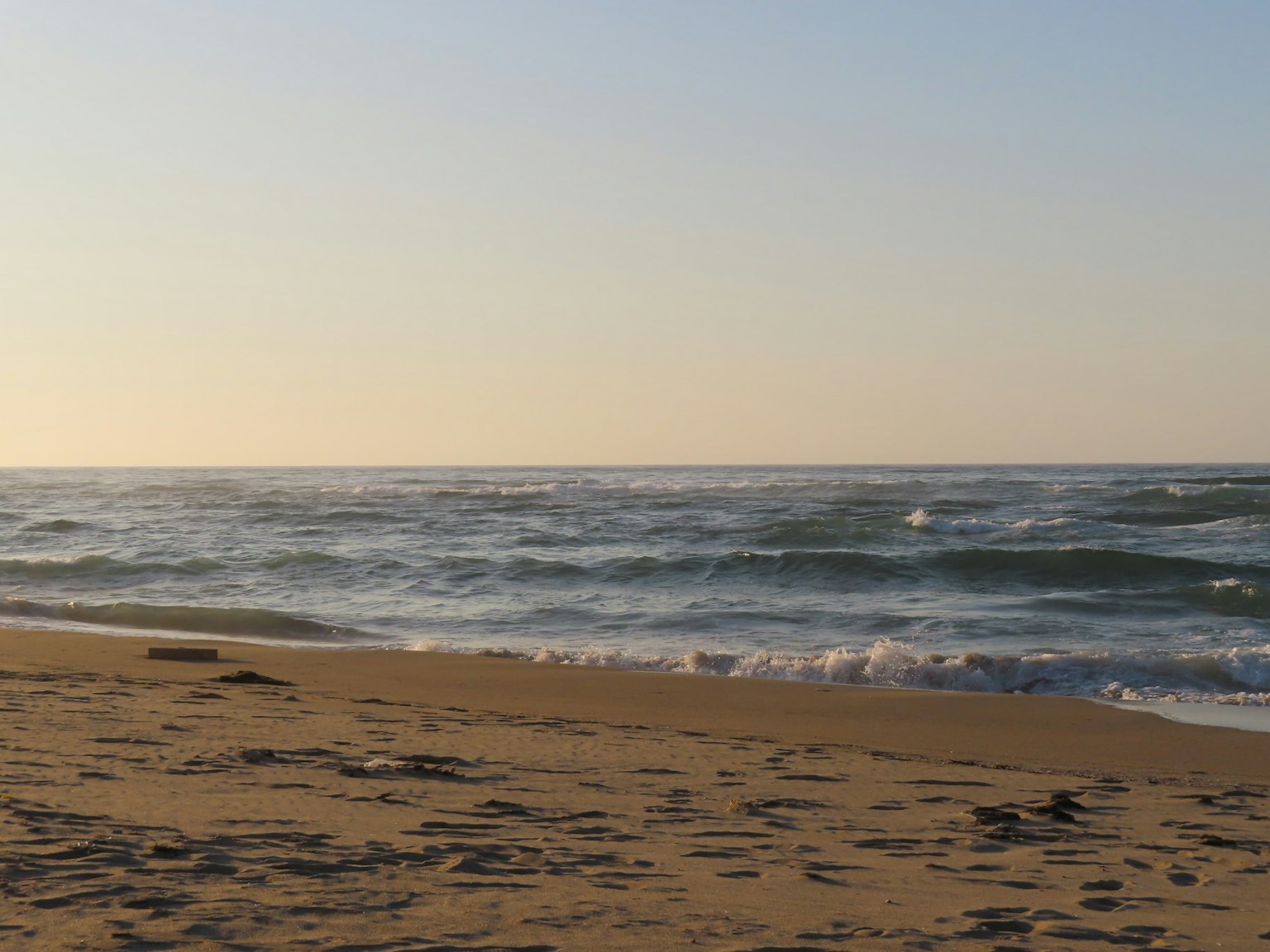 Paisaje costero con olas y playa de arena al atardecer