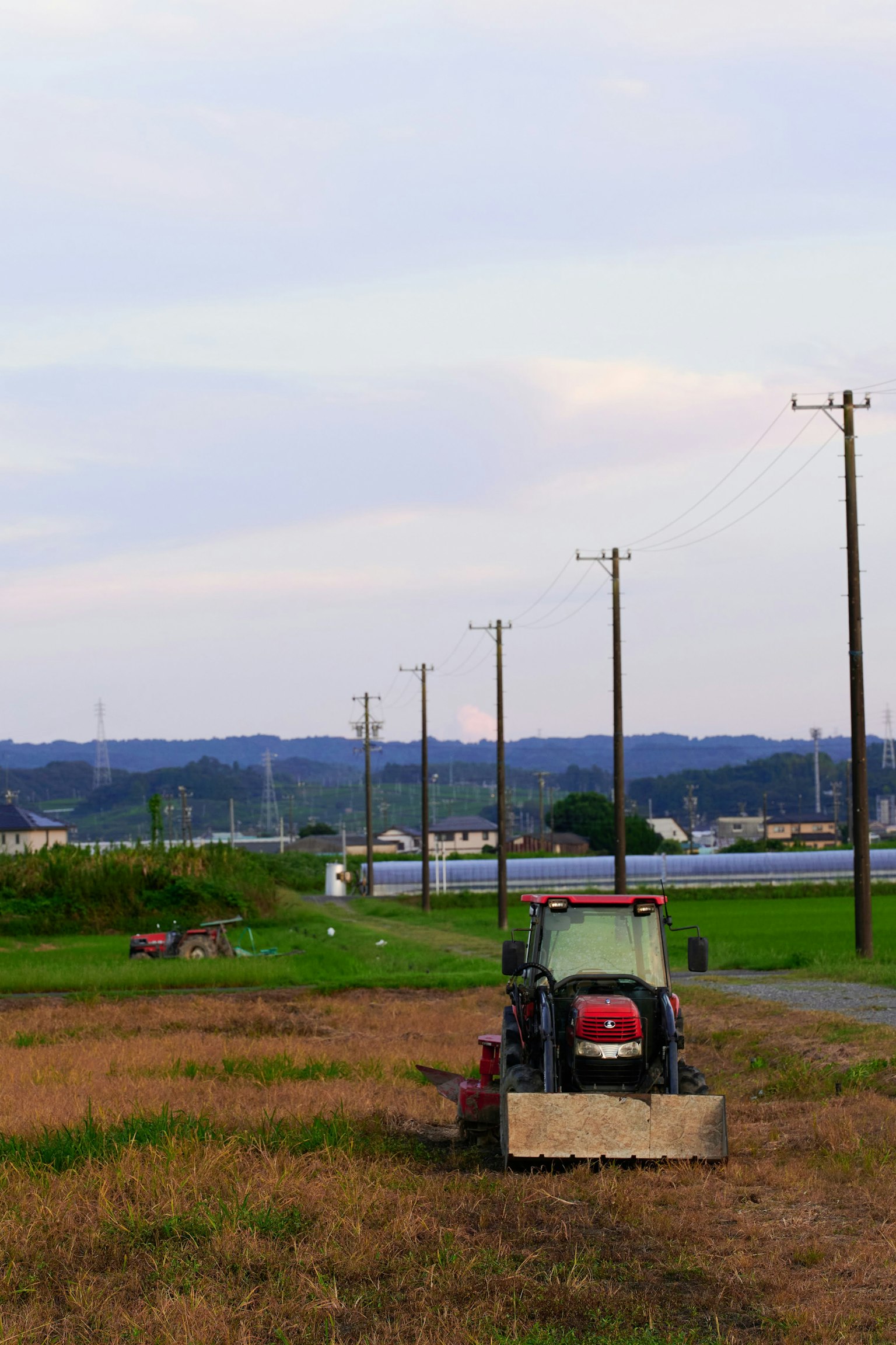 A rural landscape featuring a tractor and lined utility poles