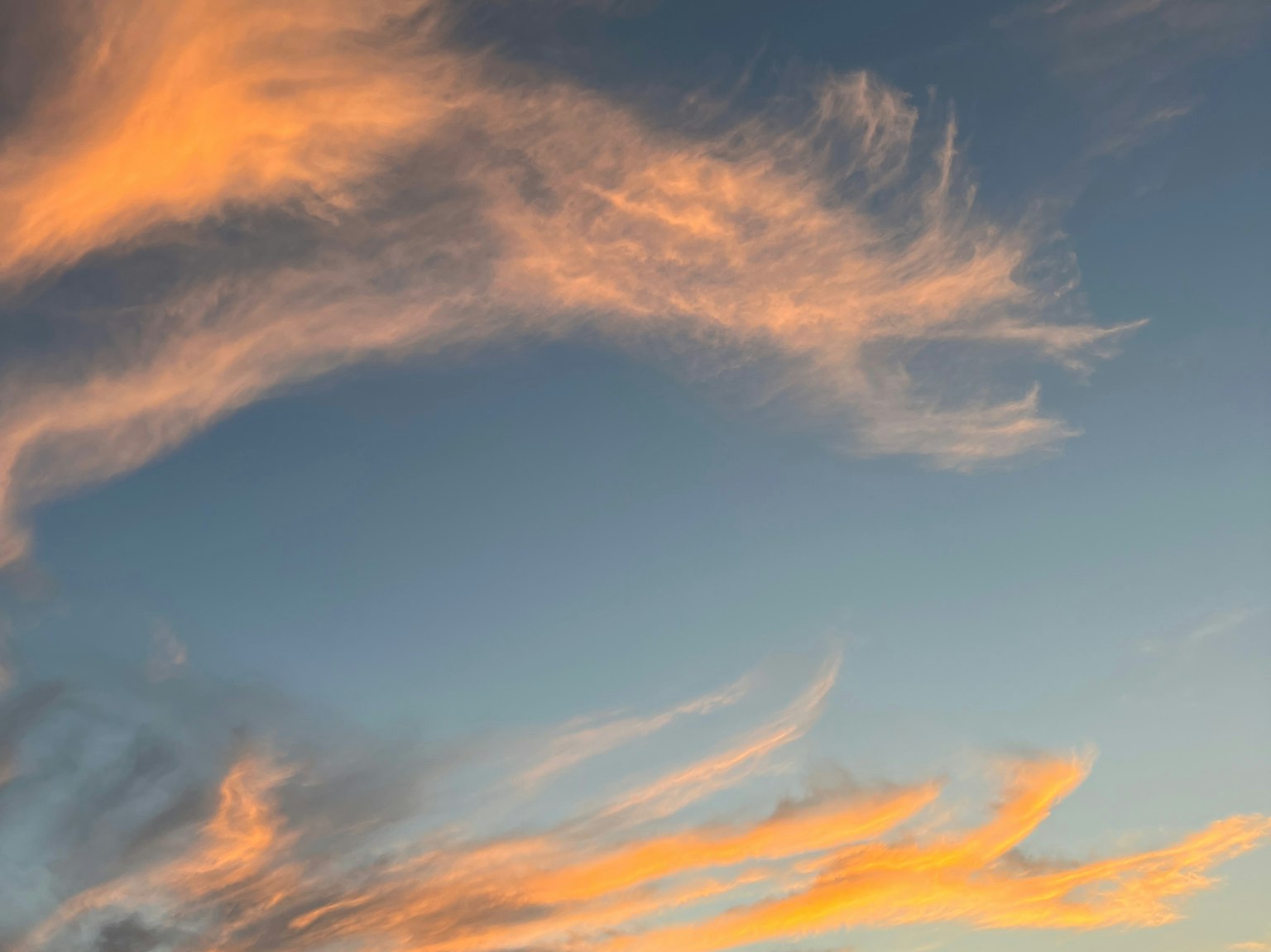 Awan oranye di langit biru saat matahari terbenam