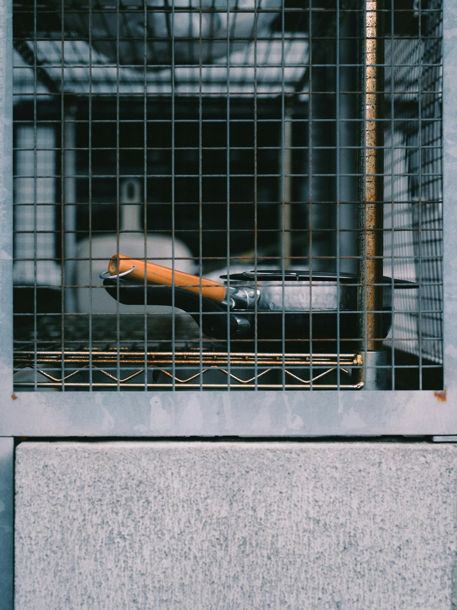 一个空盘子和一个橙色工具放在金属网格围绕的空间里