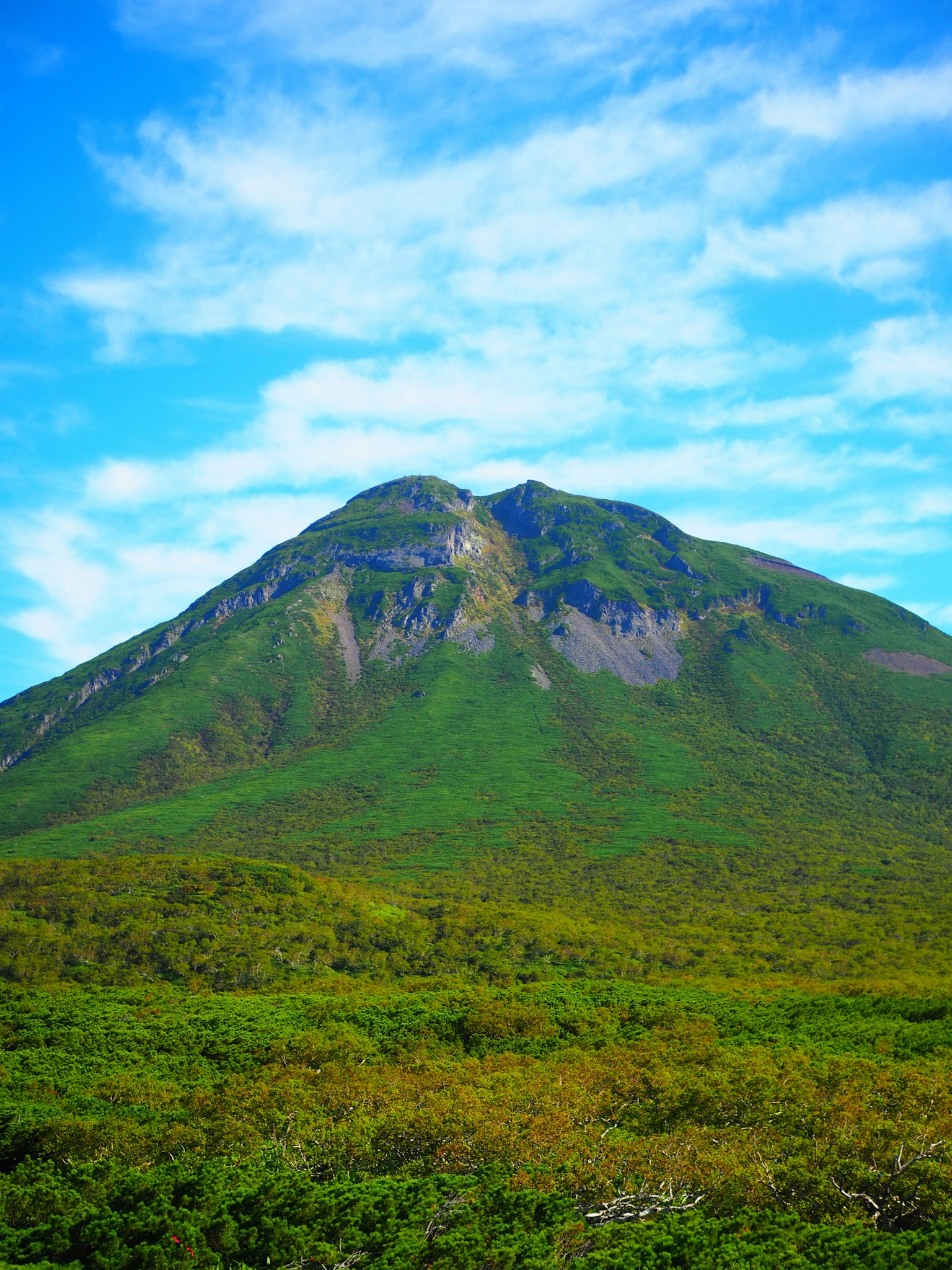 A beautiful landscape with a green mountain under a blue sky