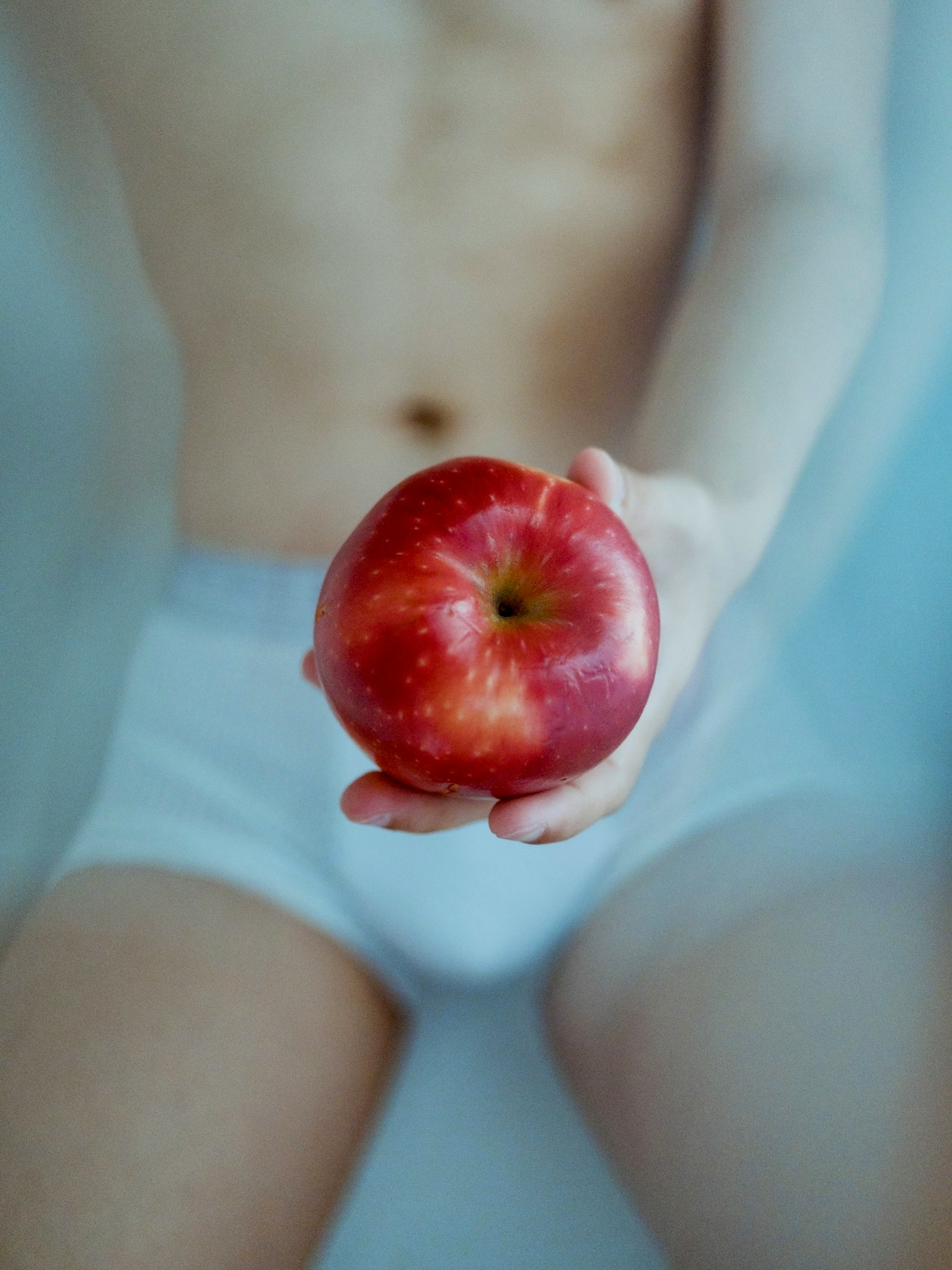 赤いリンゴを持つ子供の手が映る画像