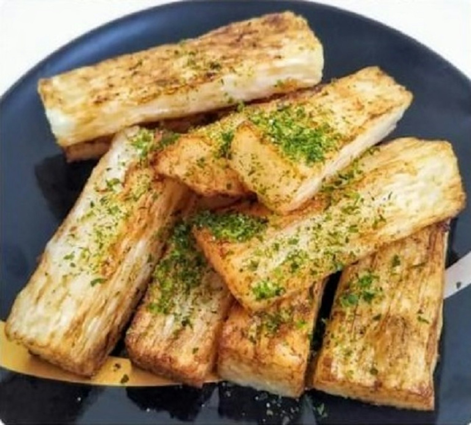 黑色盘子上的炸根菜条和绿色调料