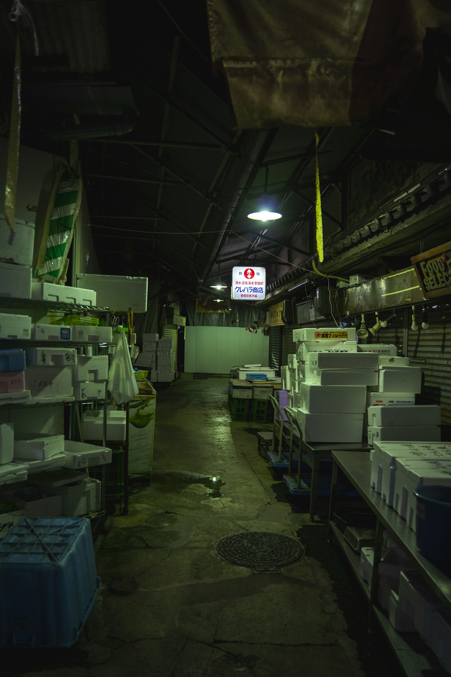 Corridoio di mercato poco illuminato fiancheggiato da scatole e scaffali