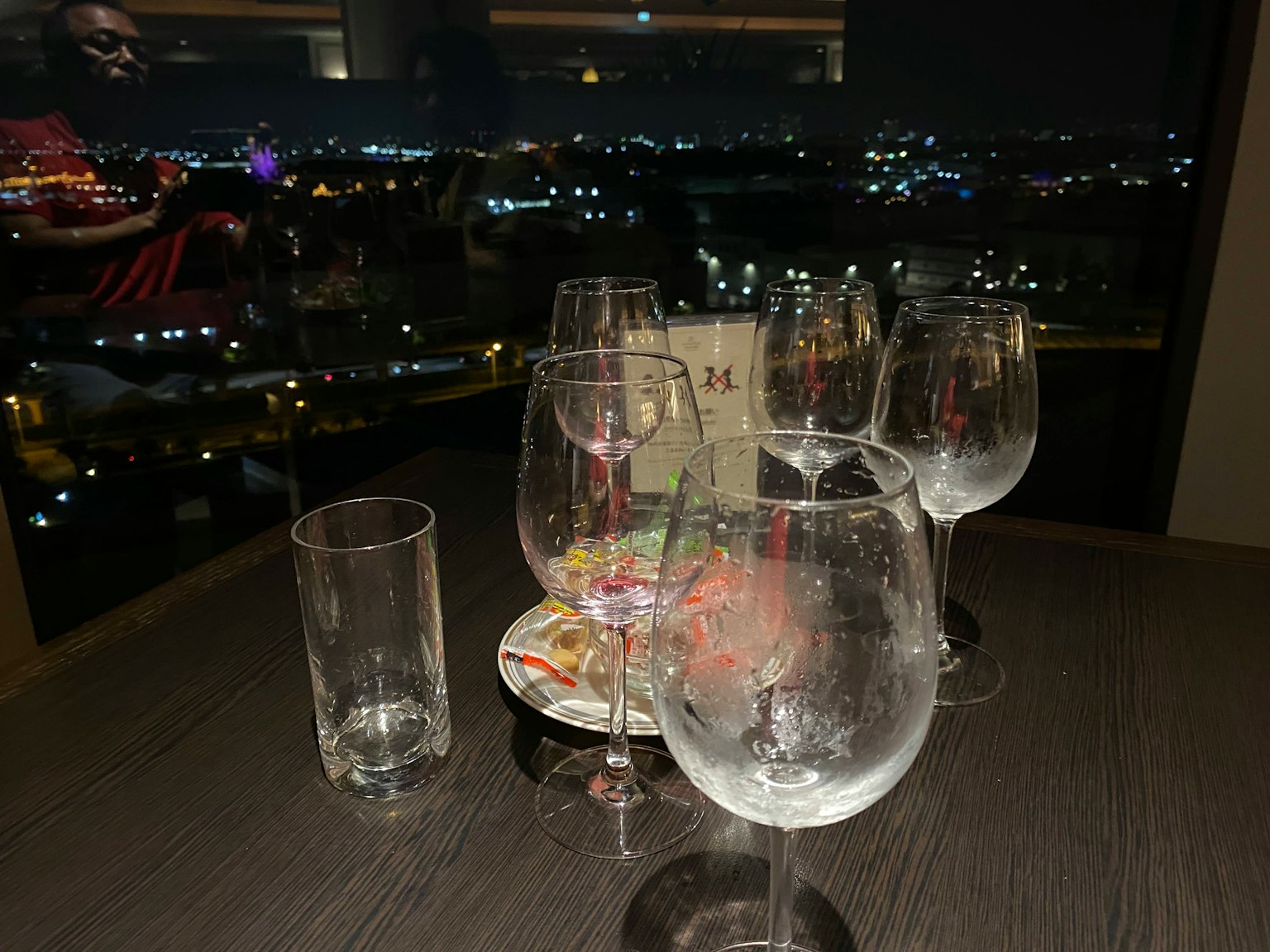 Tisch mit verschiedenen Gläsern und einer Stadtansicht bei Nacht