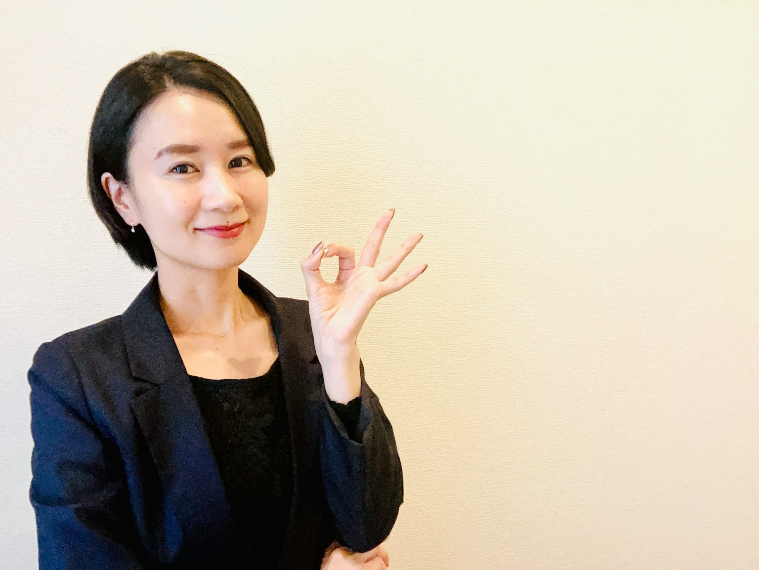 一位穿着商务西装的女性用手指做出OK手势