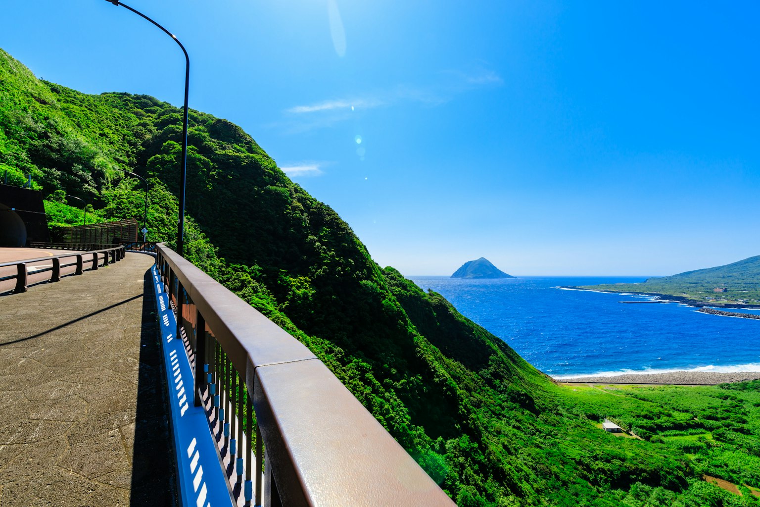 Scenic view of a coastal road with lush green hills and blue ocean