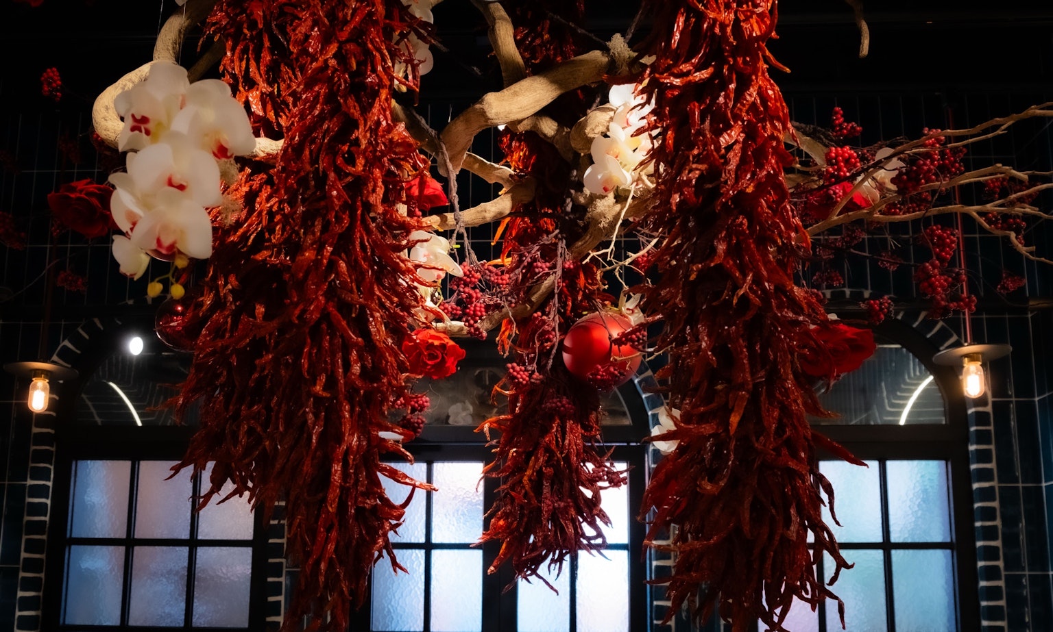 Œuvre d'art décorative avec des piments rouges et des fleurs blanches suspendues à des branches