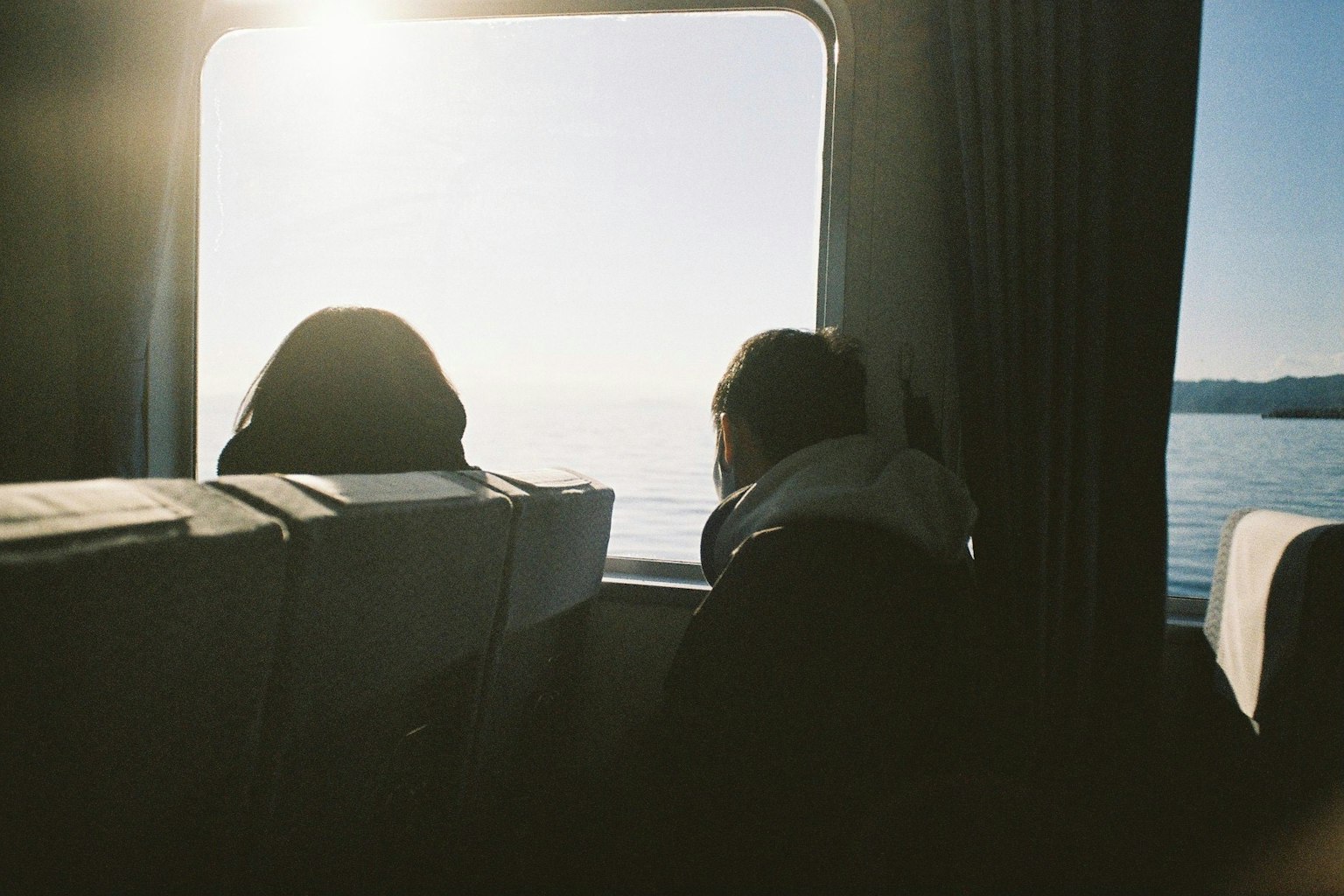 두 명의 승객이 창 밖의 바다를 바라보고 있다
