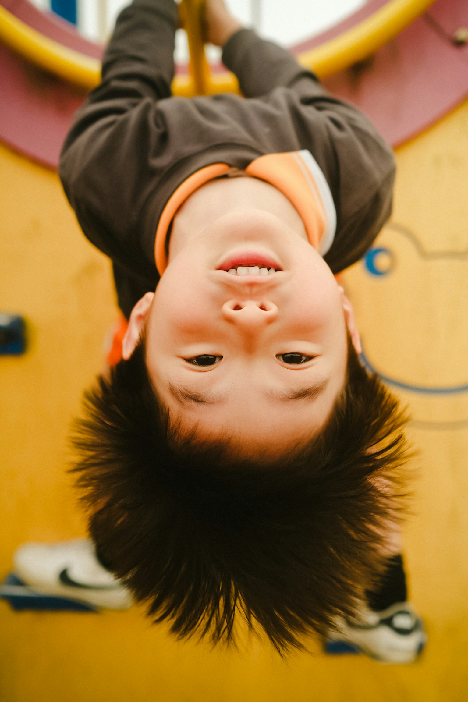 Child hanging upside down on a playground equipment