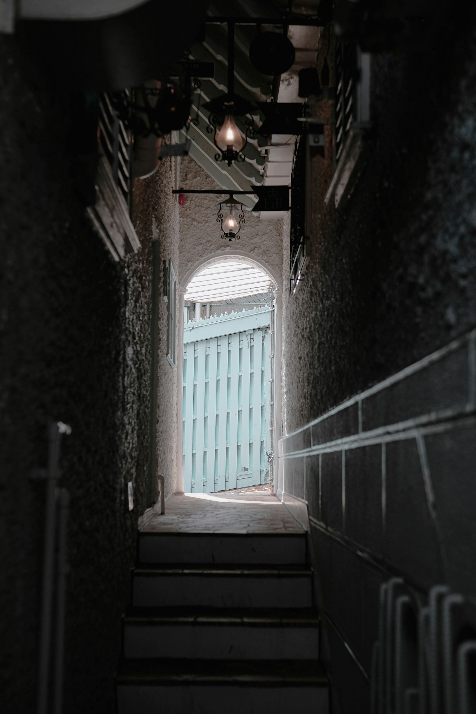 Corridoio stretto che conduce a una porta blu con illuminazione soffusa