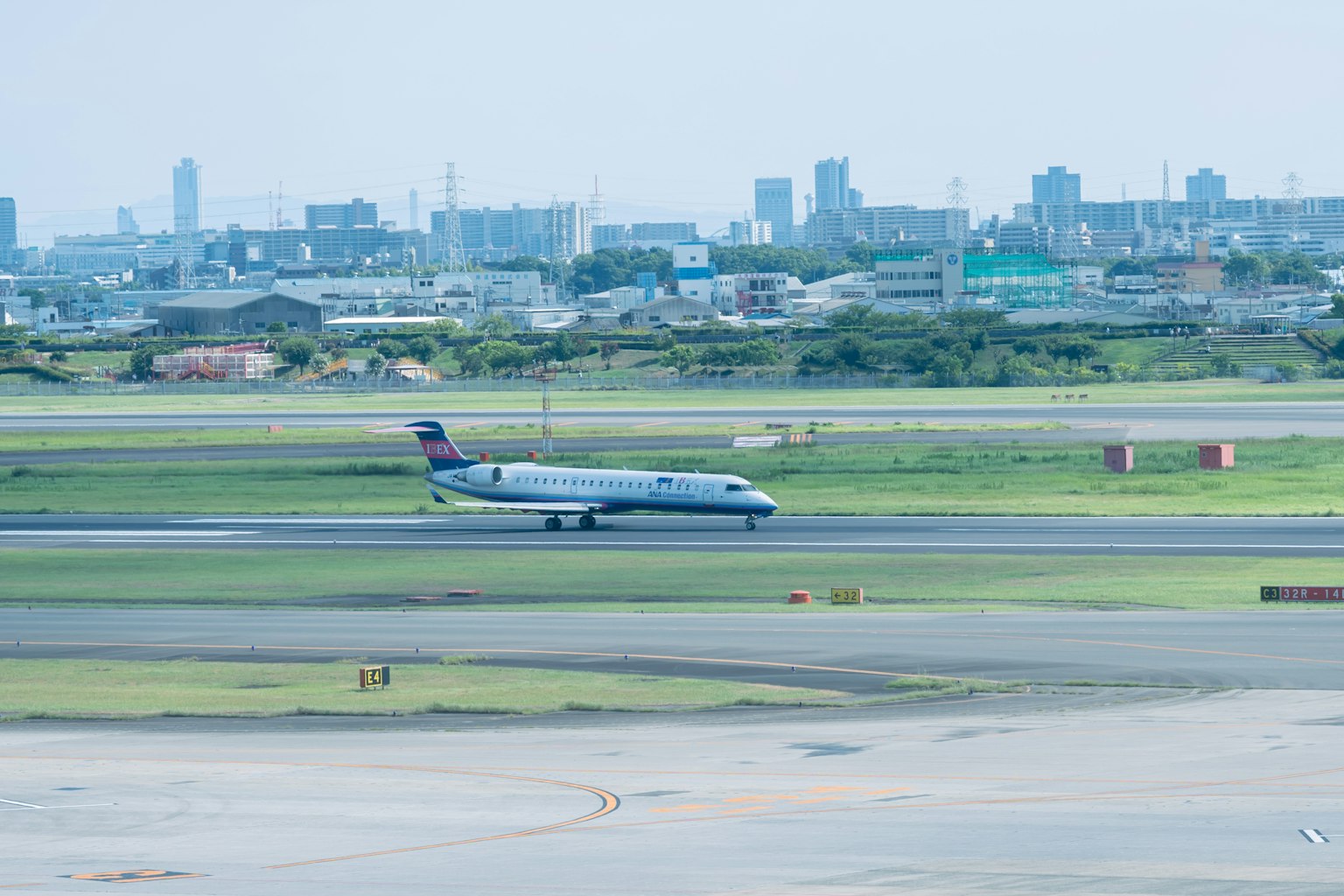Avión despegando en un aeropuerto con el horizonte de la ciudad de fondo
