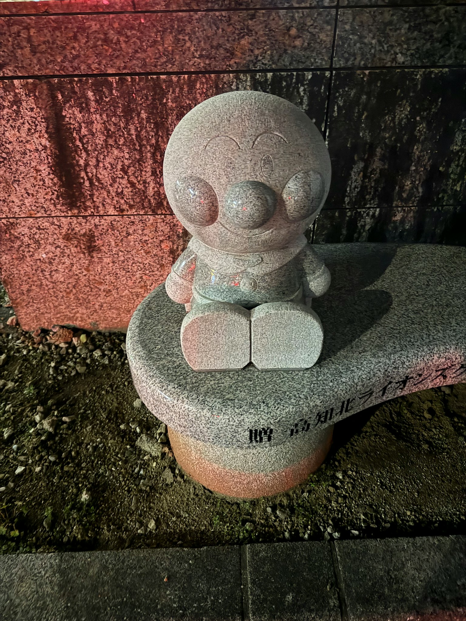 밤에 공원에 앉아 있는 돌 캐릭터 조각상