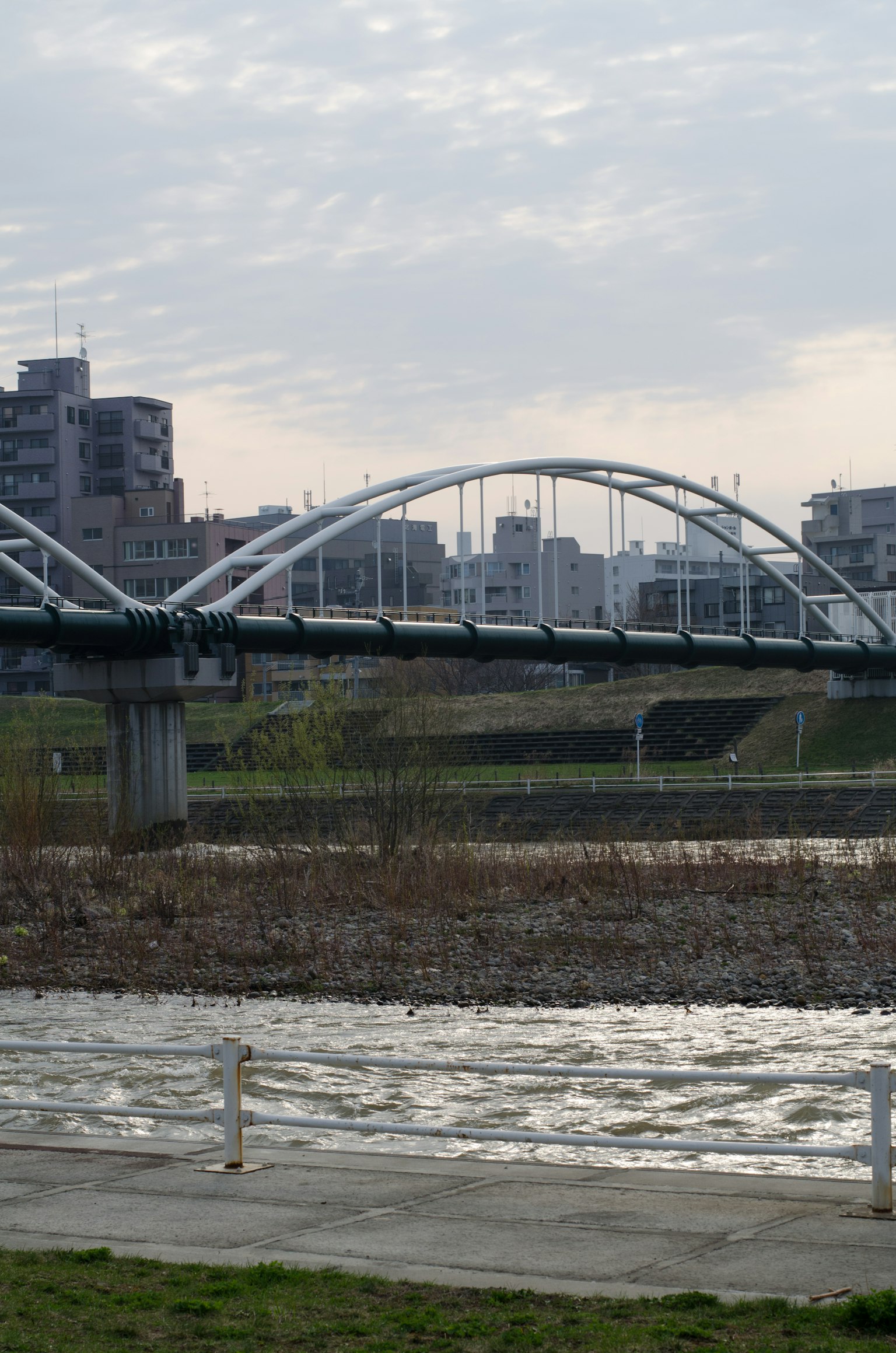 Weißer Bogenbrücke über einem Fluss mit umliegenden Gebäuden