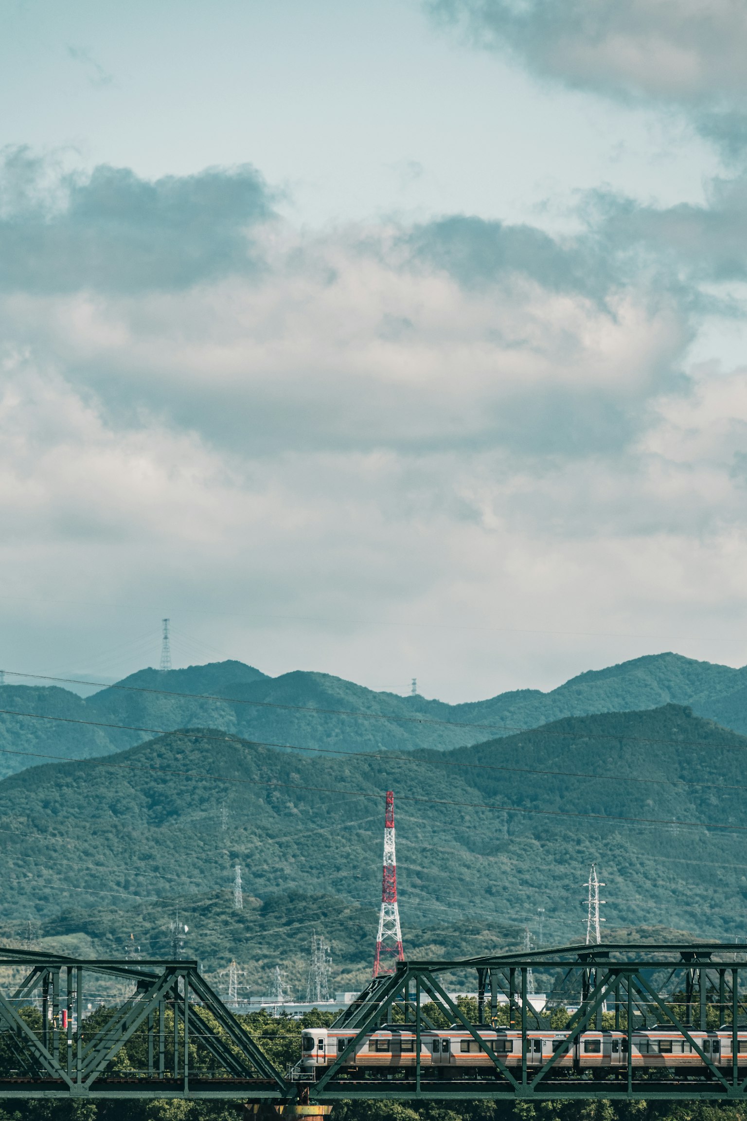 Paisaje montañoso con una torre de transmisión roja y blanca