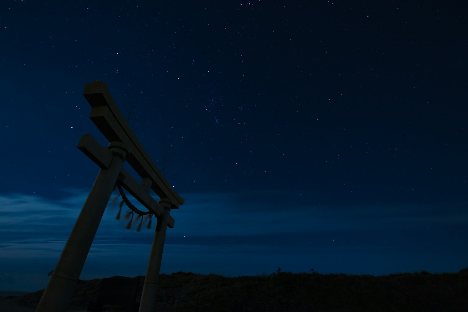Vista de un torii bajo un cielo estrellado
