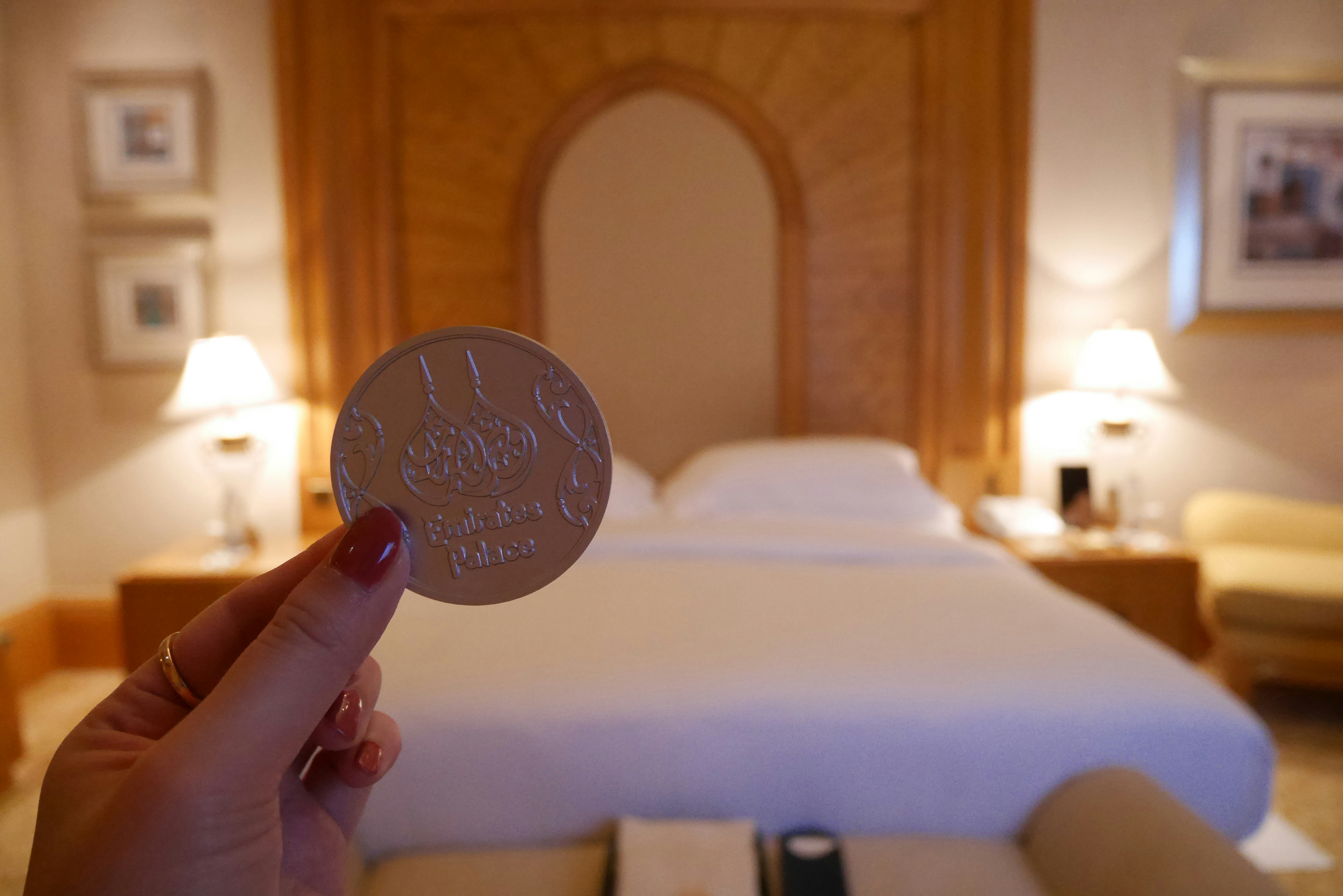Hand hält eine Hotel-Schlüsselkarte über einem Bett