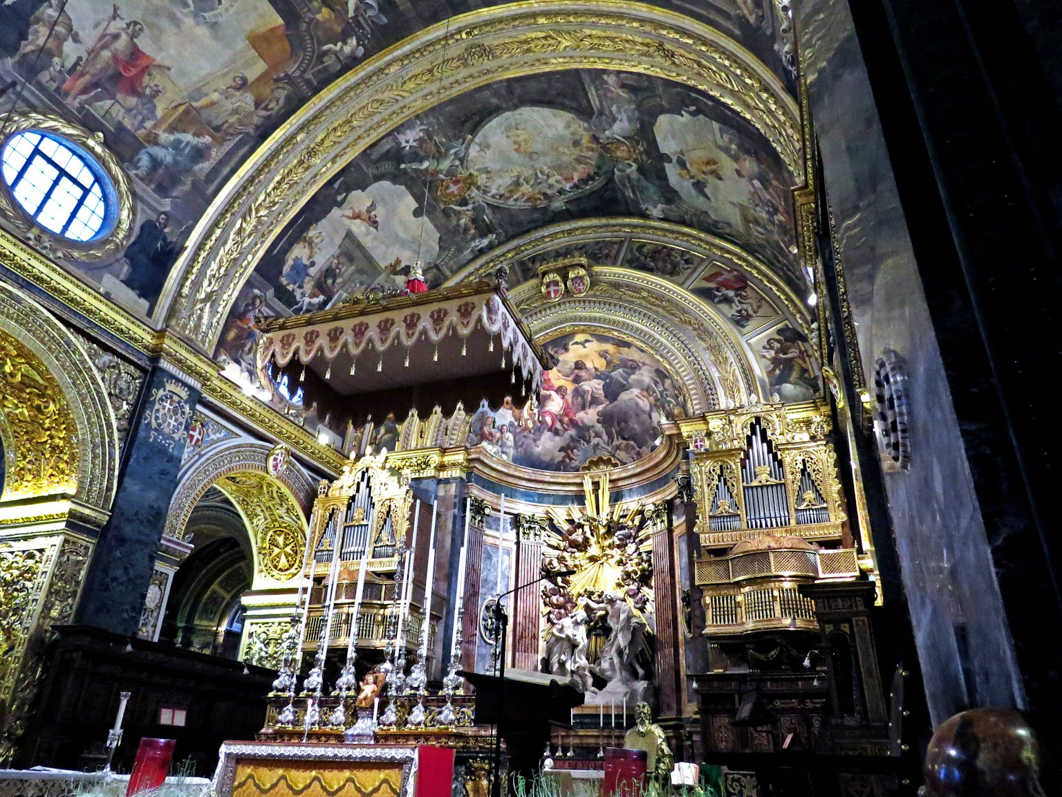 Interior of a church featuring ornate golden decorations and a grand ceiling mural