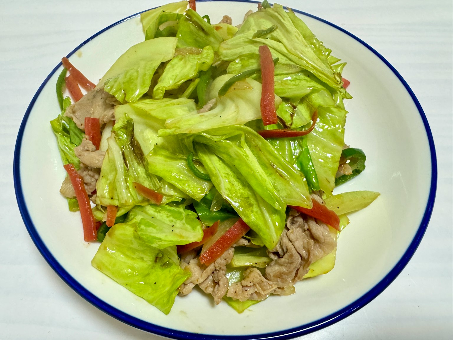 Un plato de ensalada de lechuga fresca y pimiento rojo con carne en rodajas