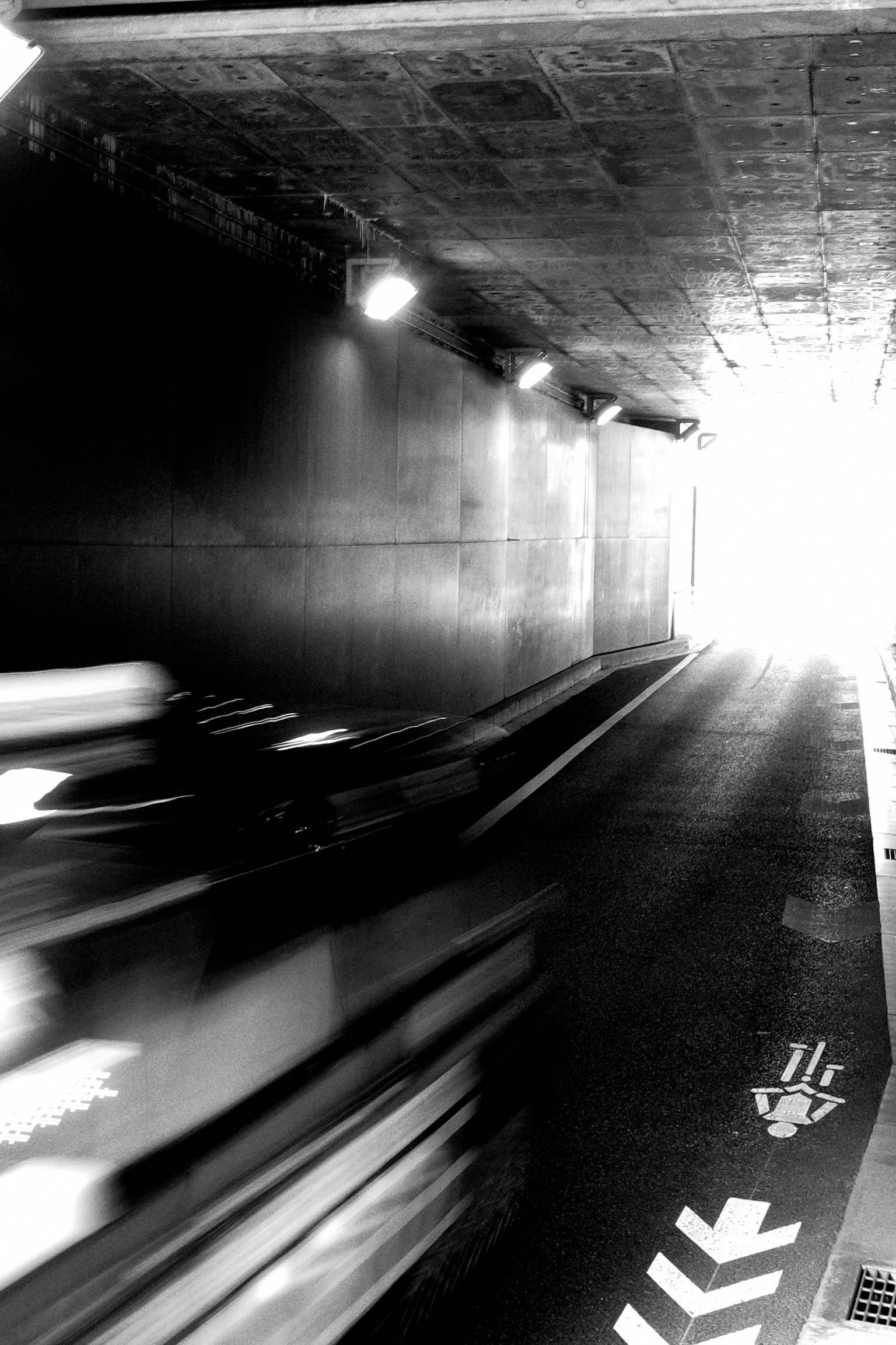 トンネルの中を通過する車両の動きが捉えられたモノクロ画像 明るい出口が見える