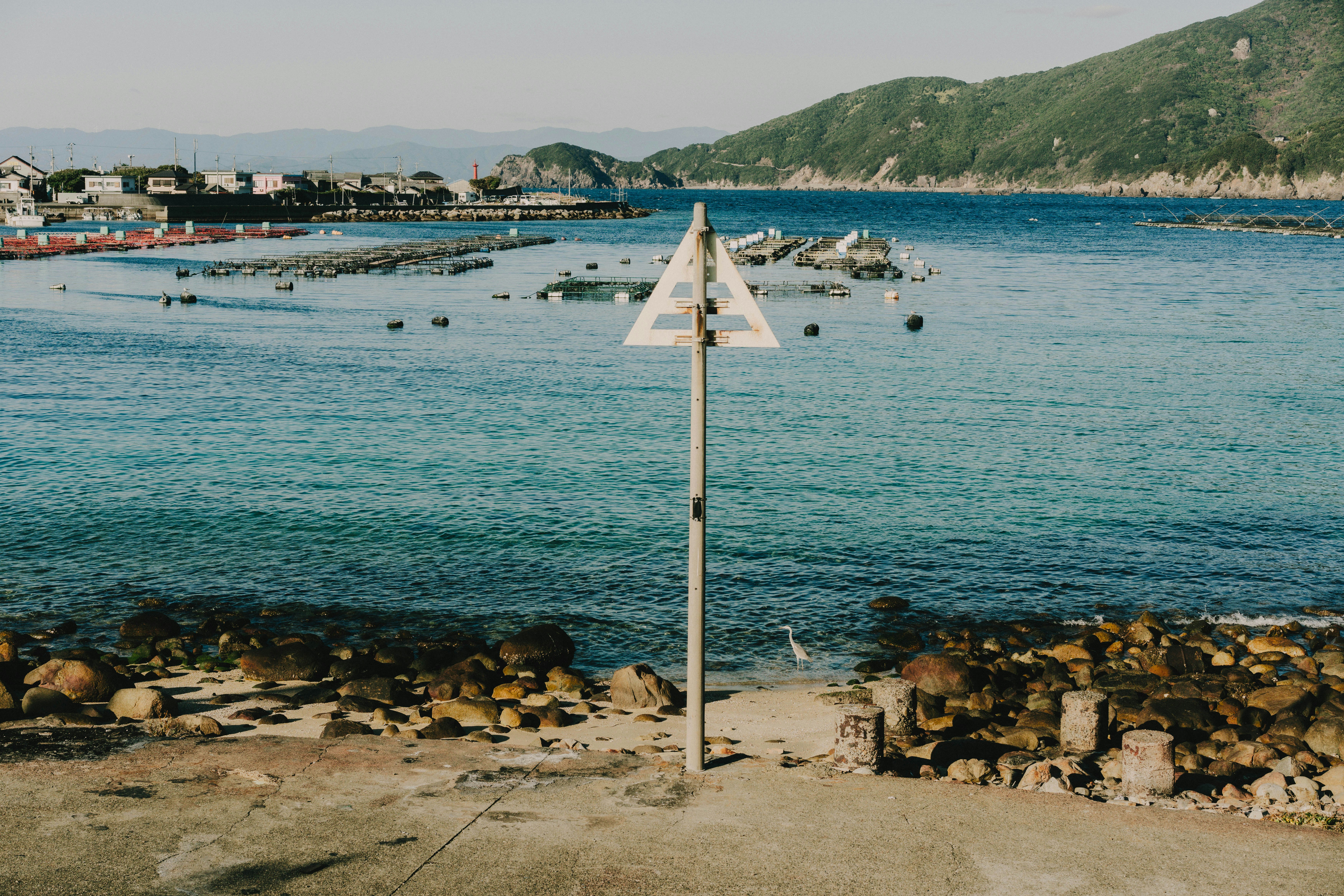 海辺の砂浜と沖合の小さな船や岩礁のある風景
