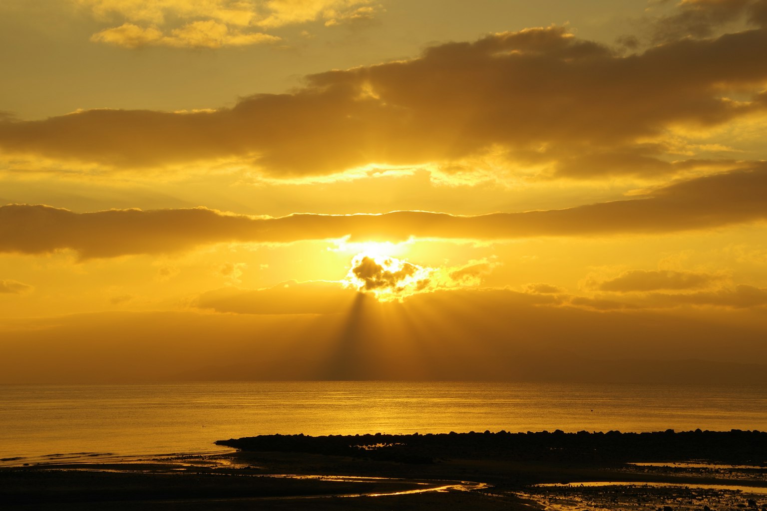 Tramonto dorato che brilla attraverso le nuvole sul mare