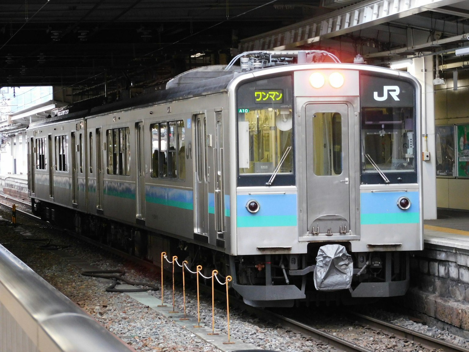 Kereta JR dengan garis biru berhenti di stasiun
