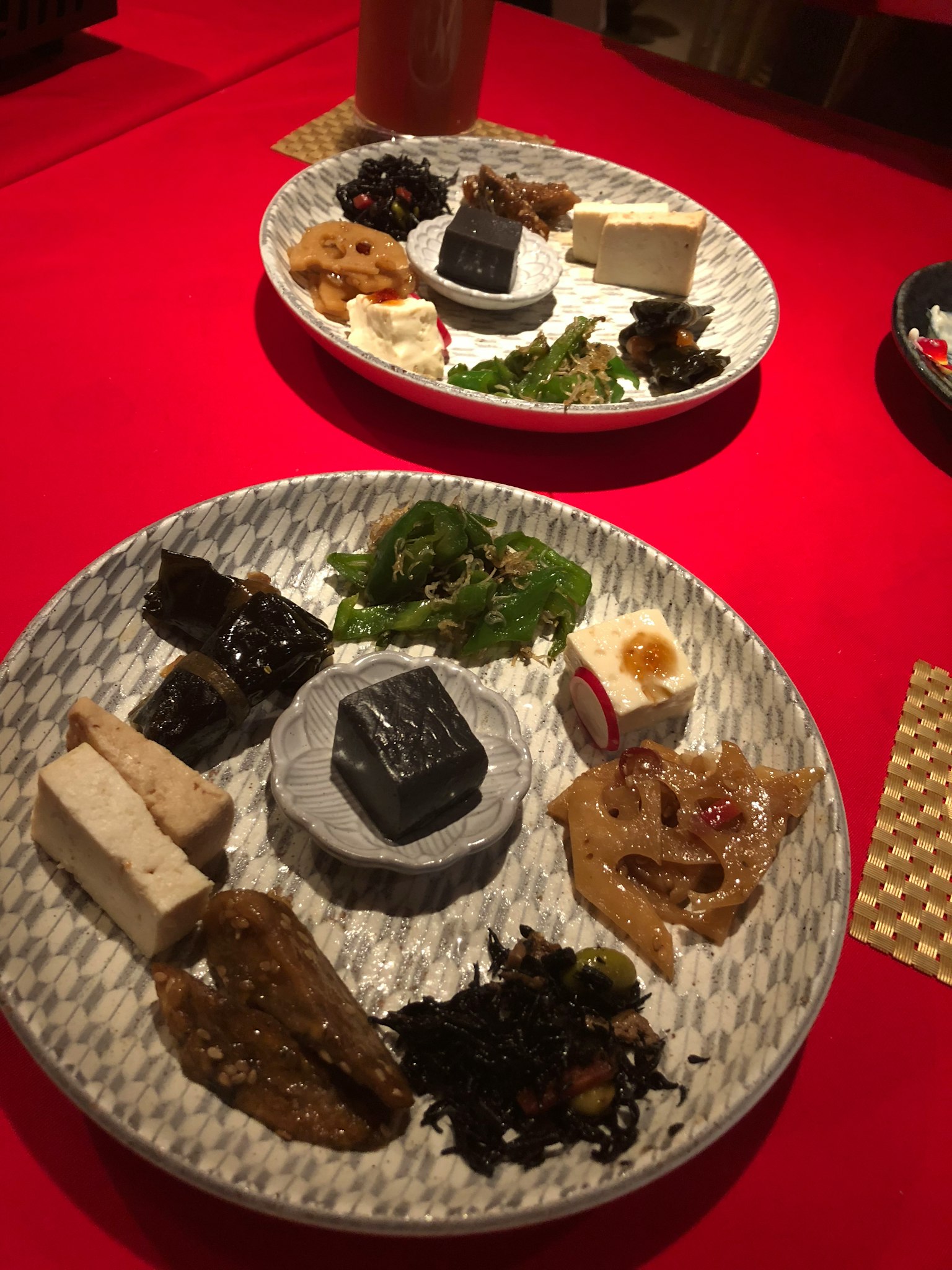 Due piatti di antipasti giapponesi assortiti su un tavolo rosso