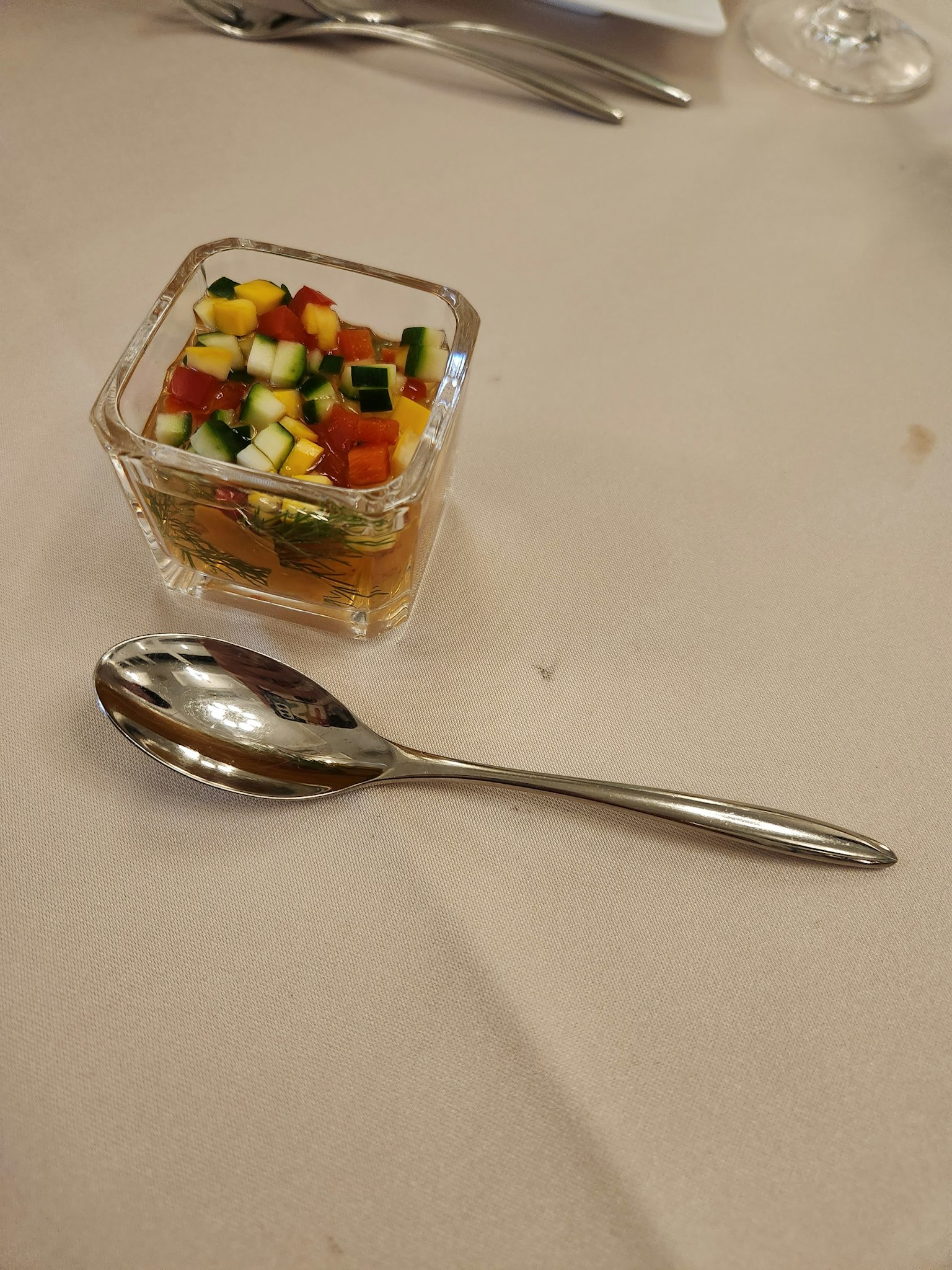 Ensalada colorida en un recipiente transparente con una cuchara de plata al lado