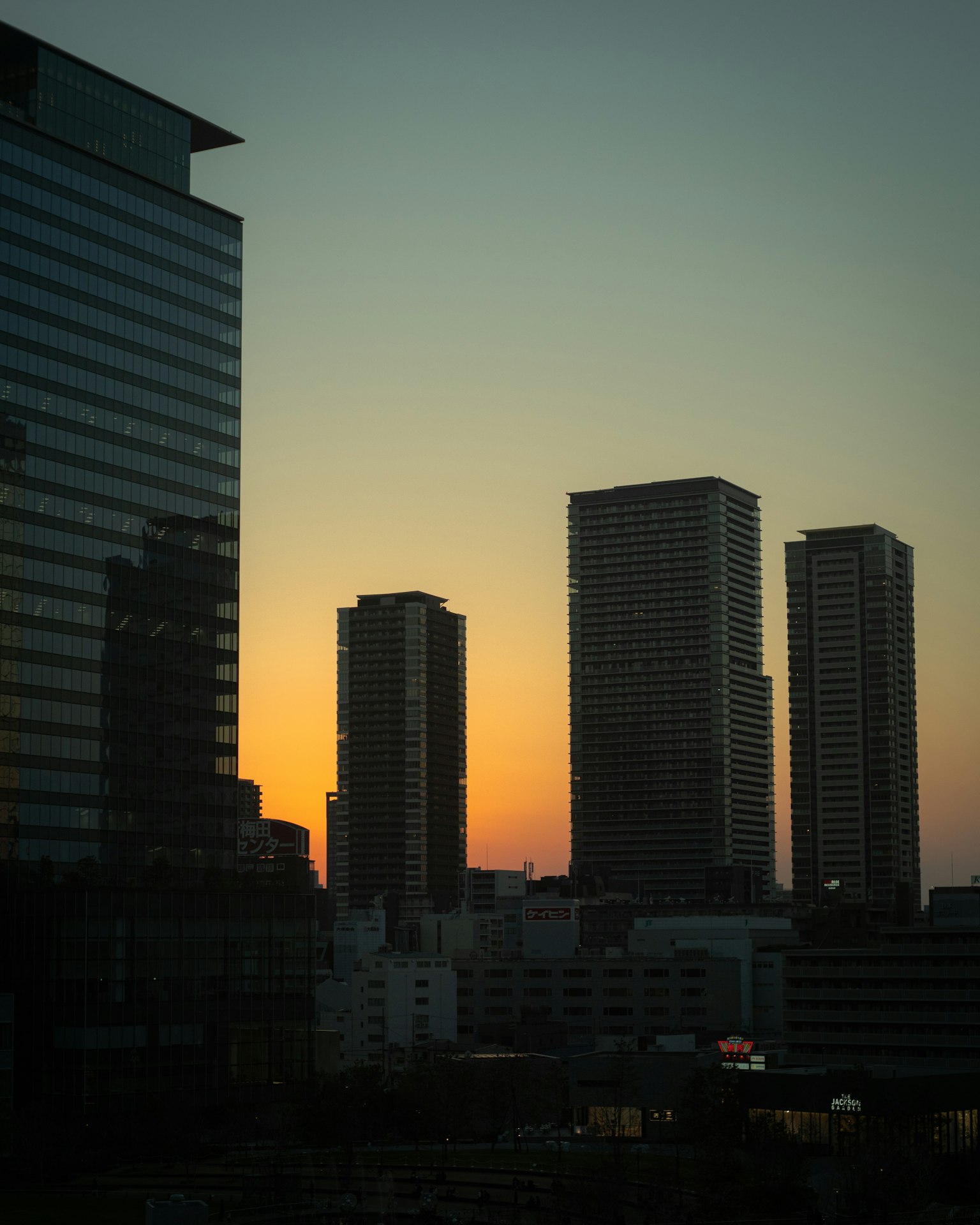 Silhouette of a city skyline with high-rise buildings against a sunset