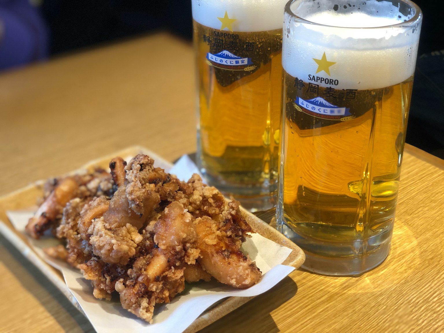 맥주 두 잔과 튀긴 치킨 접시의 이미지