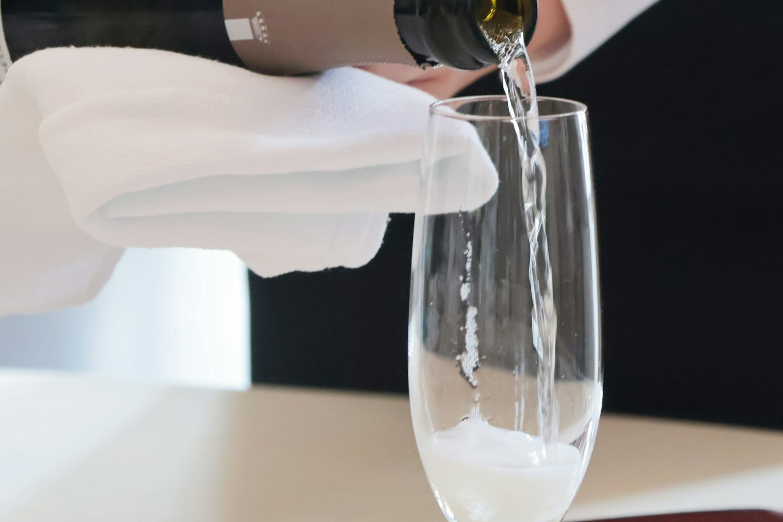 Close-up of white wine being poured into a champagne glass