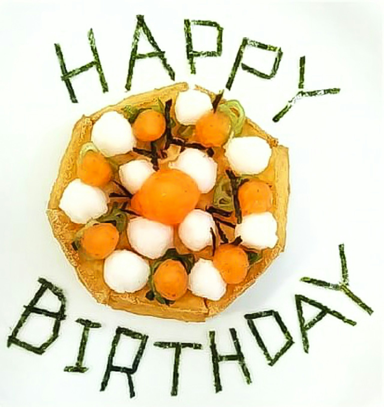 Un pastel de cumpleaños decorado con frutas y crema con las palabras 'HAPPY BIRTHDAY' hechas de hojas verdes