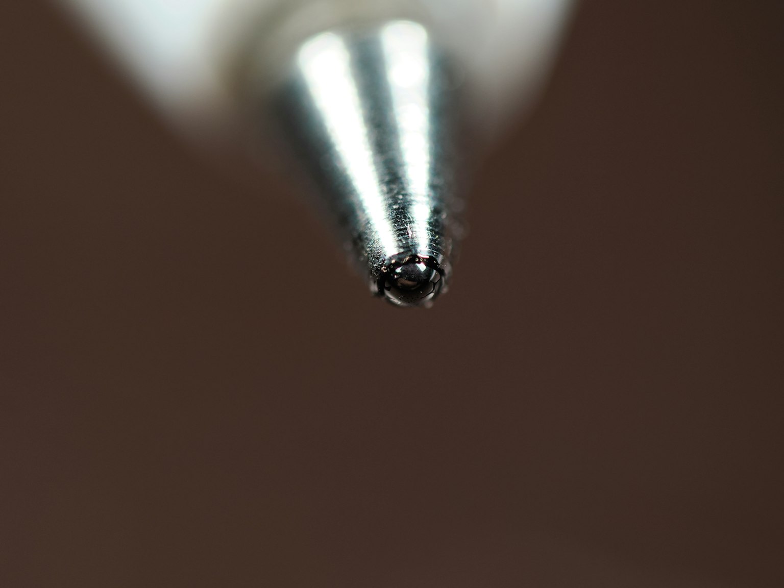 金属製のペン先のクローズアップ画像 黒いインクの滴が見える