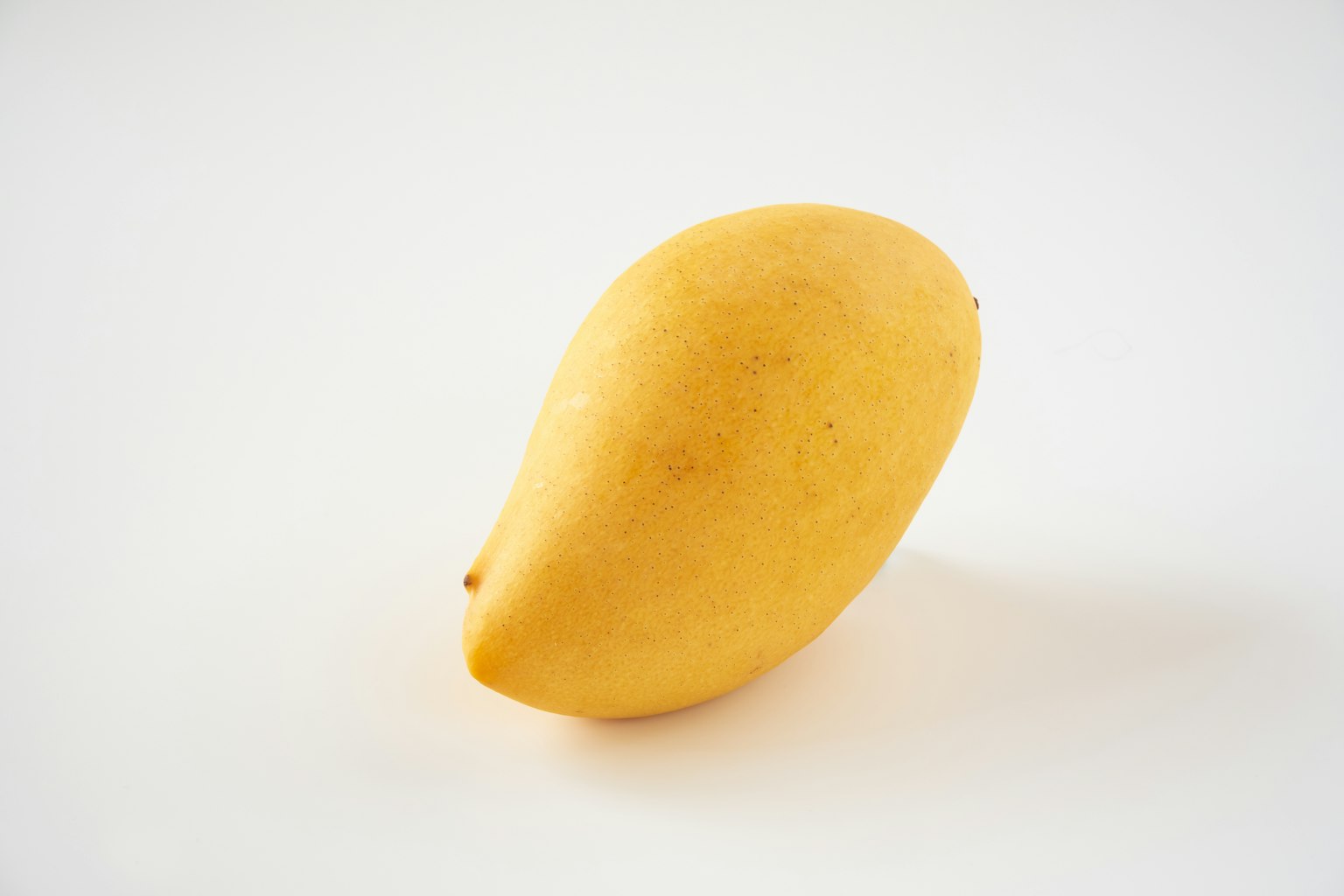 Una mango gialla posata su uno sfondo bianco
