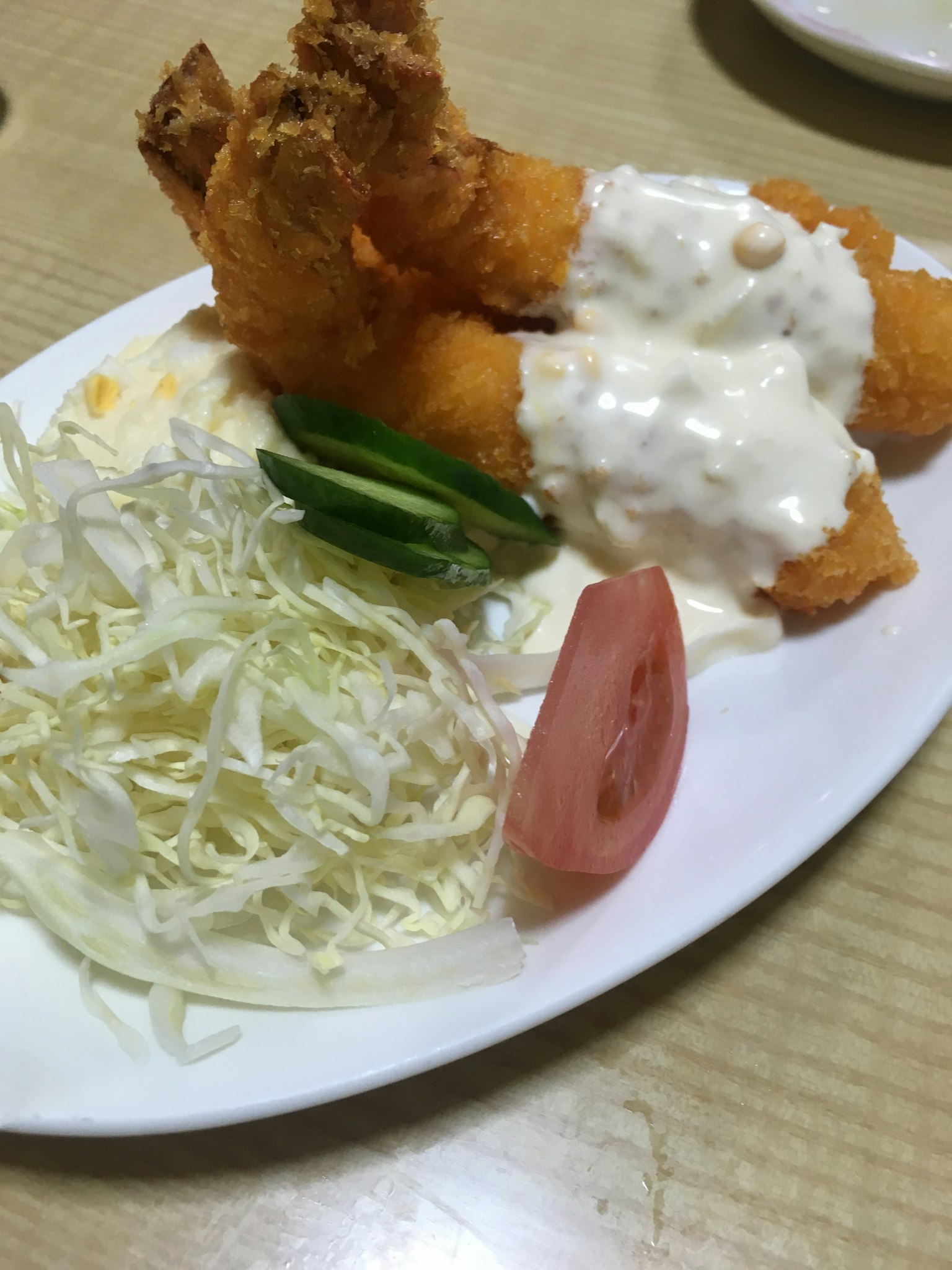 กุ้งทอดพร้อมซอสครีมเสิร์ฟในจานสีขาวพร้อมกับกะหล่ำปลีและมะเขือเทศ