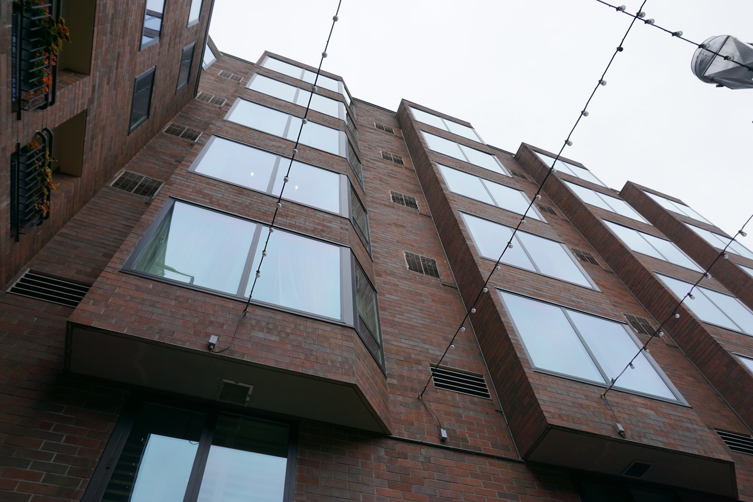 Bâtiment moderne en briques vu d'en bas avec de grandes fenêtres en verre