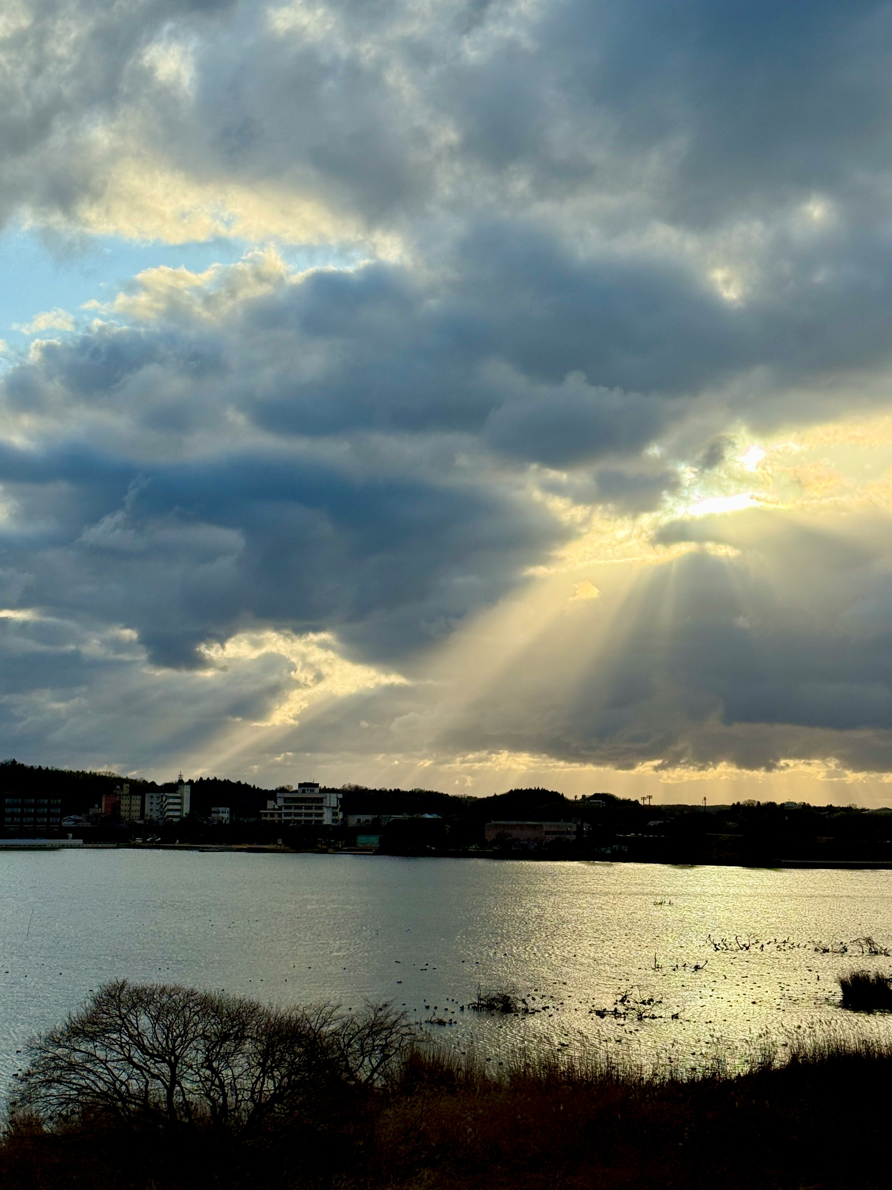 雲が広がる空と光の筋が湖に反射する風景