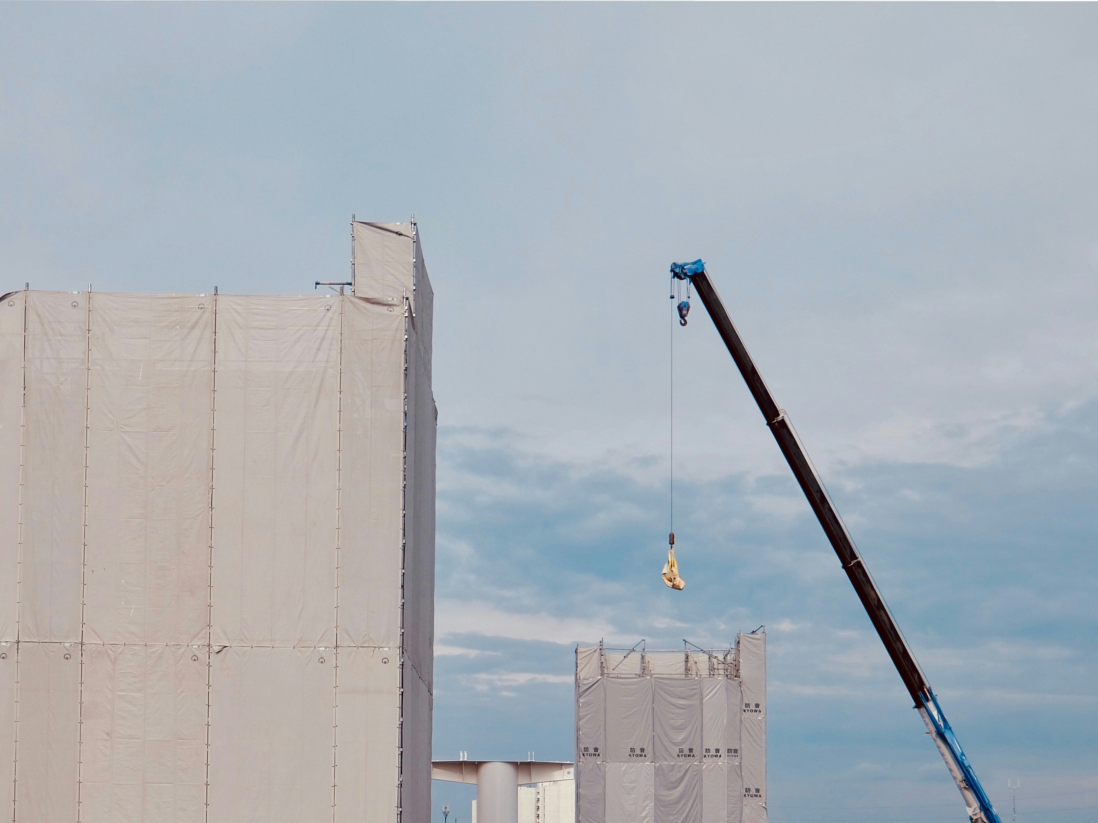 coin de chantier avec une grue soulevant une charge suspendue sur fond de ciel