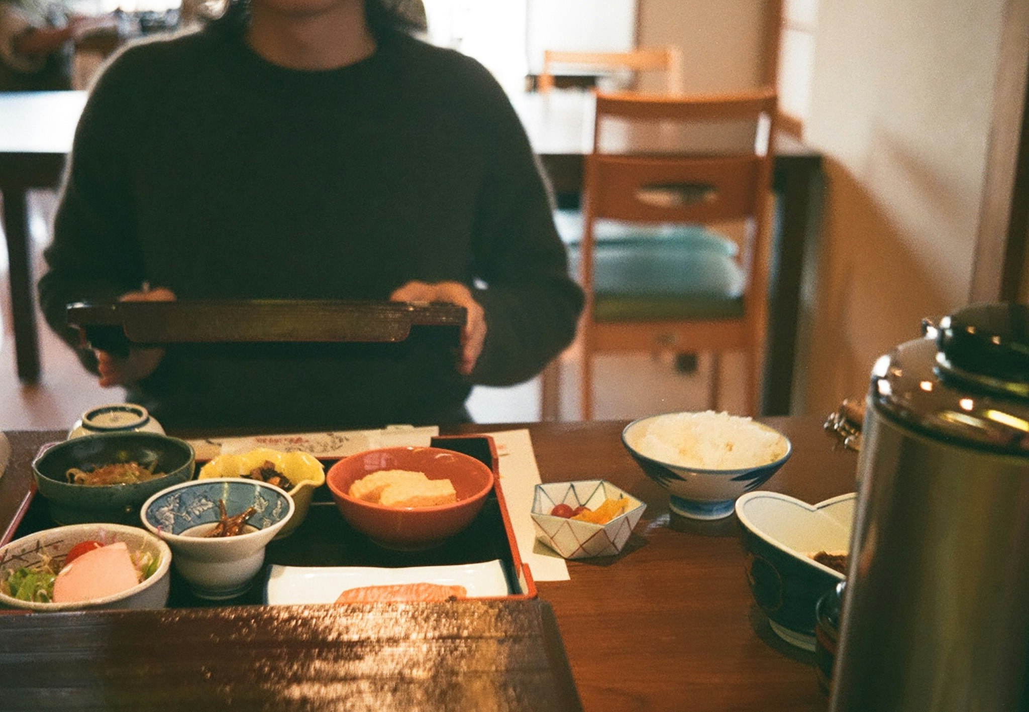 木のテーブルに並ぶ和食の小鉢と湯気のある食卓